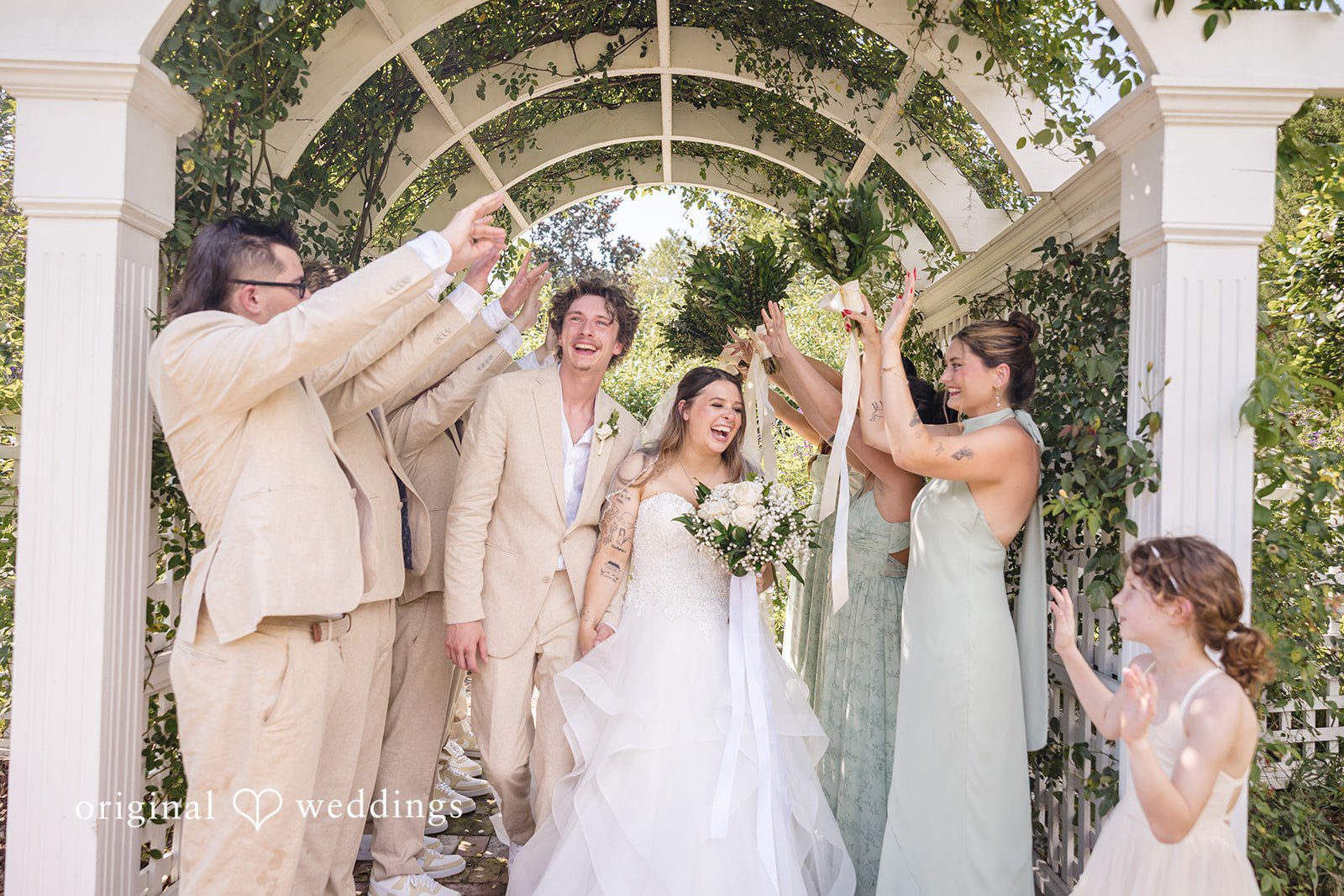 Madison + Aiden Bride and groom celebrating with their wedding party beneath the garden arbor at Magnolia Plantation and Gardens captured by Charleston Wedding Photographers from Original Weddings