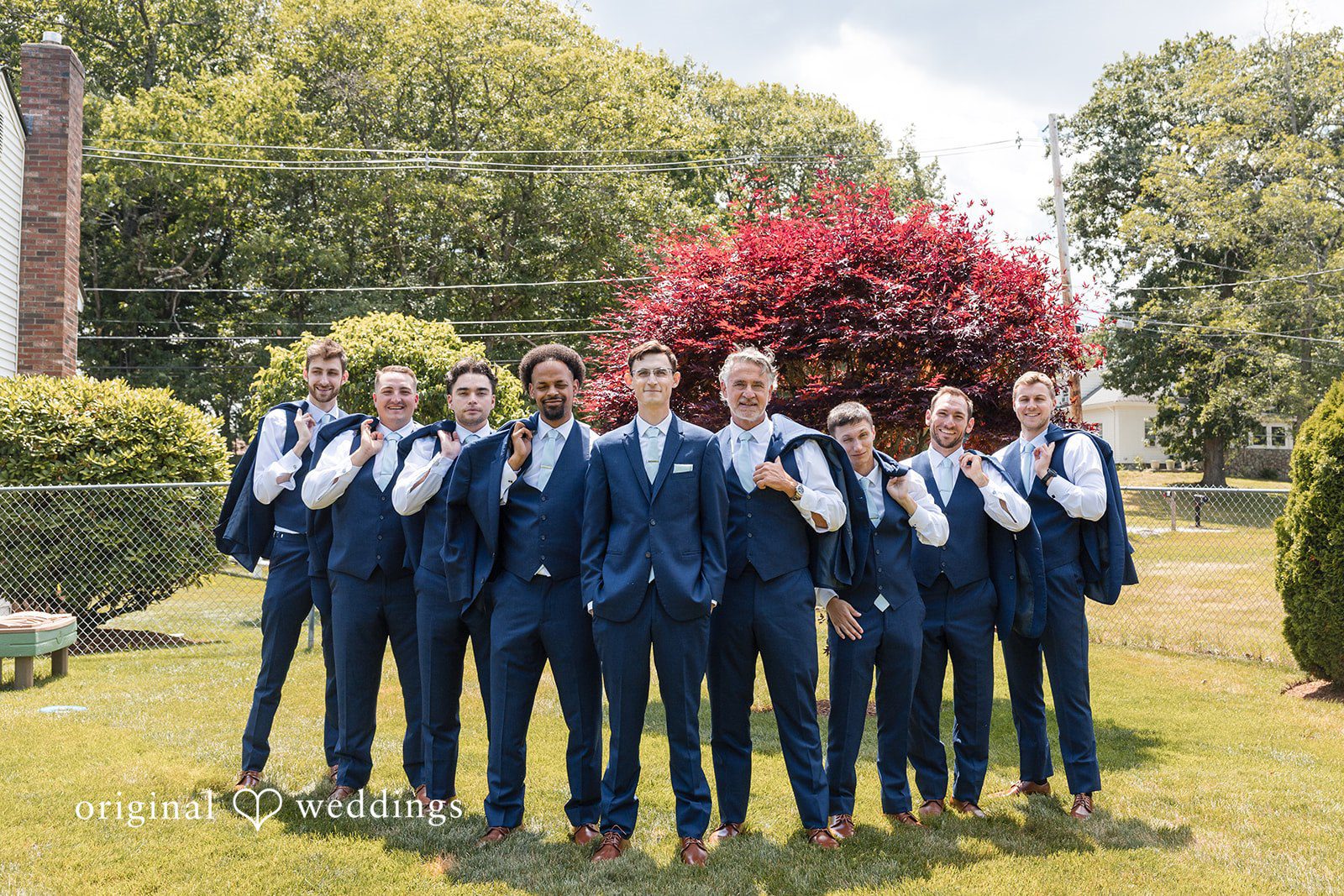 John + Emma Groom and his groomsmen standing in a row wearing blue suits.