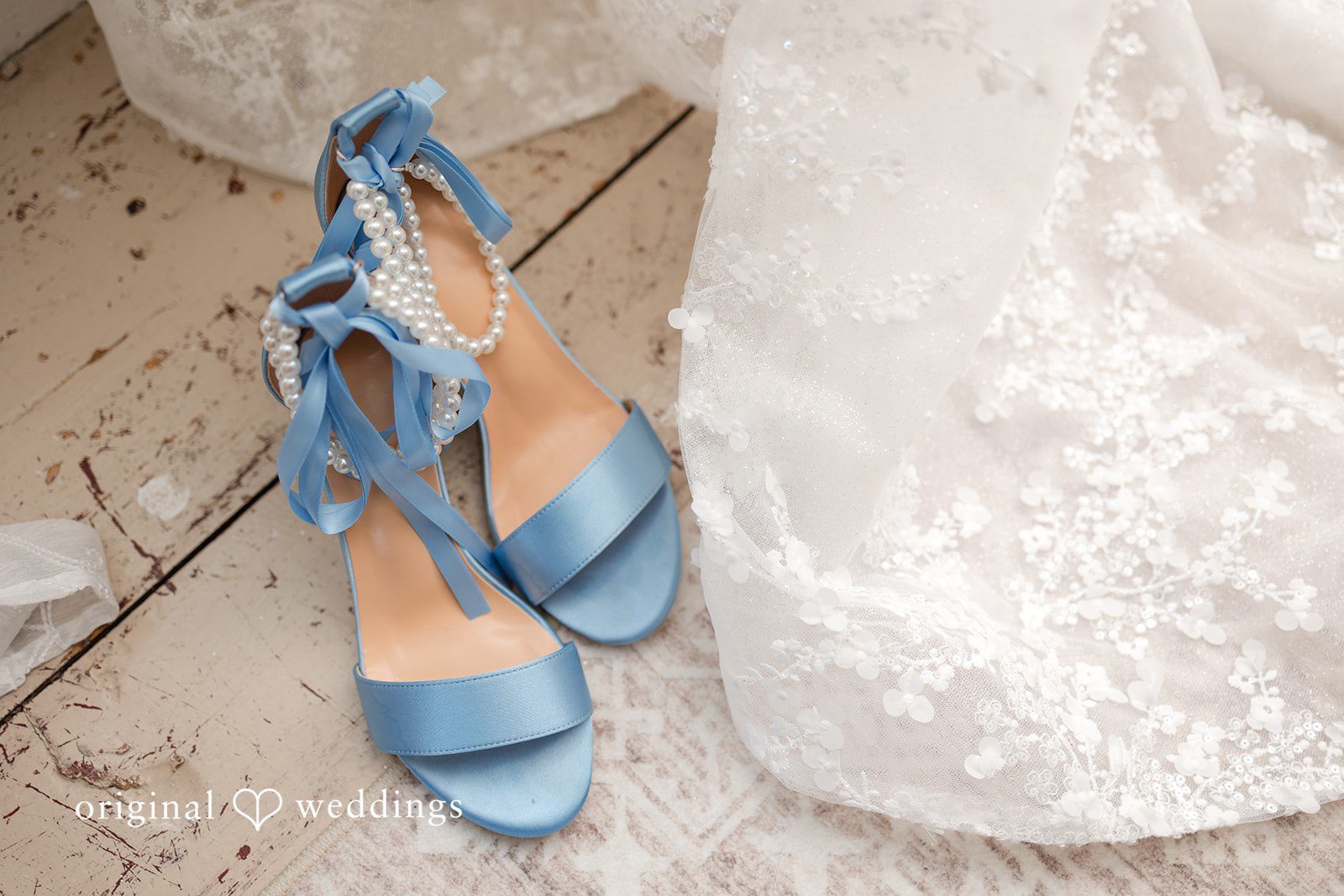 John + Emma Light blue bridal high heels next to a lace wedding dress.