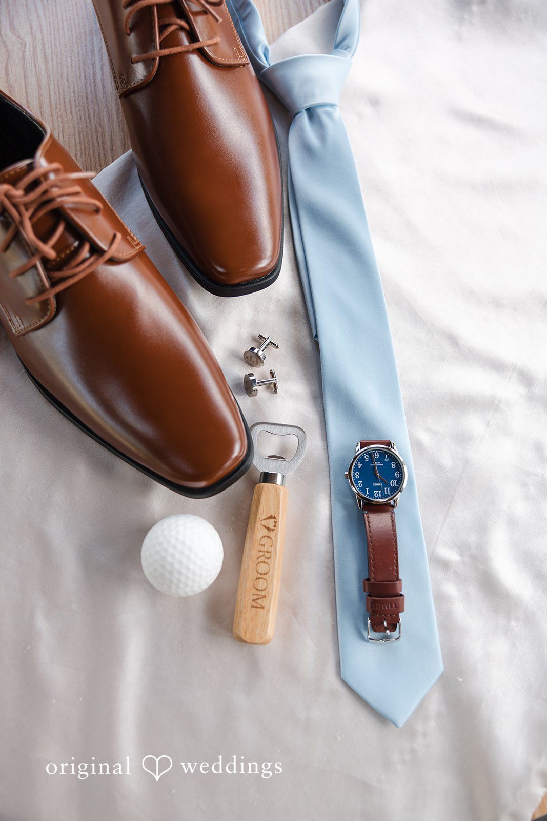 John + Emma Groom's details showing brown leather shoes, a blue tie, and accessories.