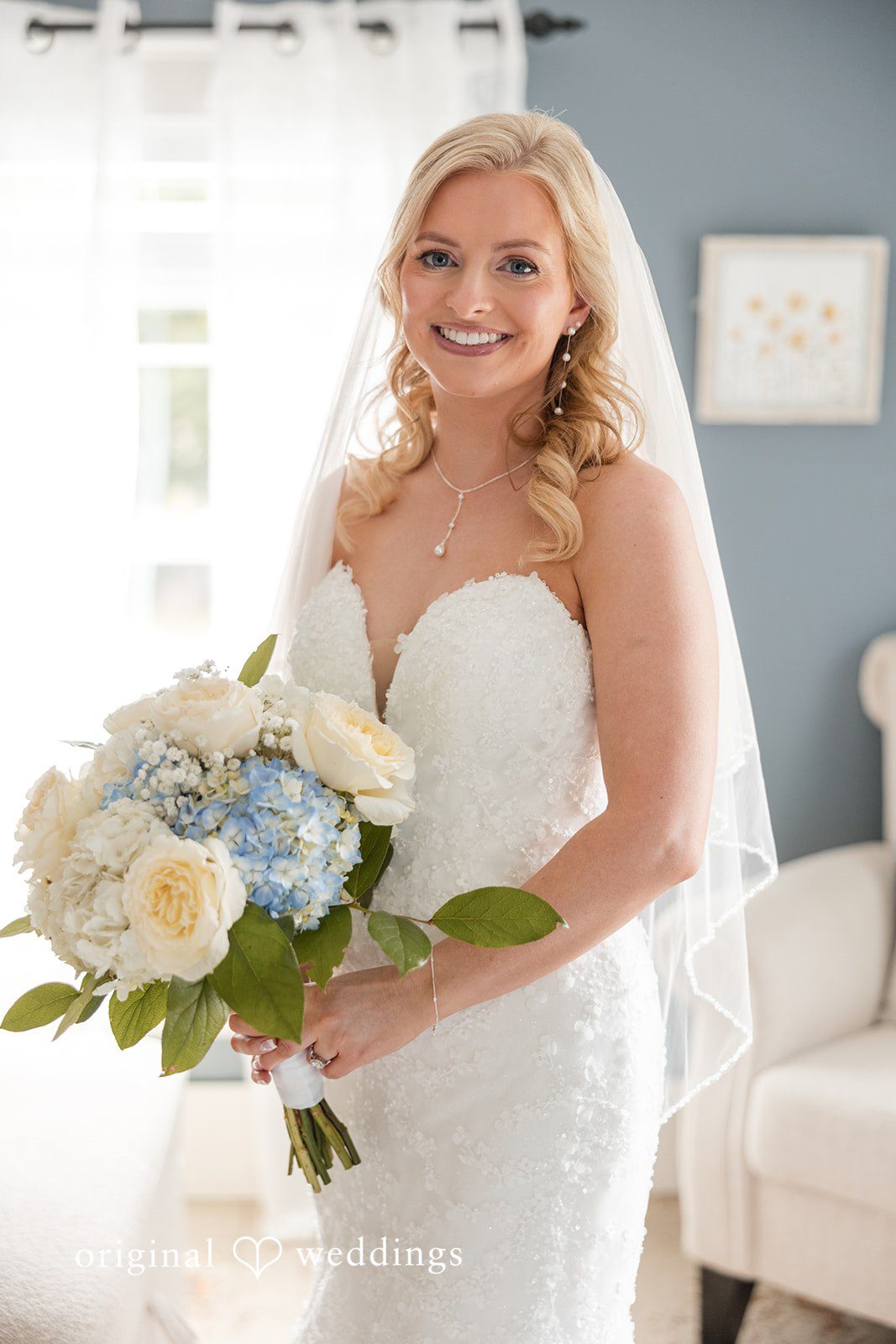 John + Emma Bride in her wedding dress holding a white and blue bouquet.
