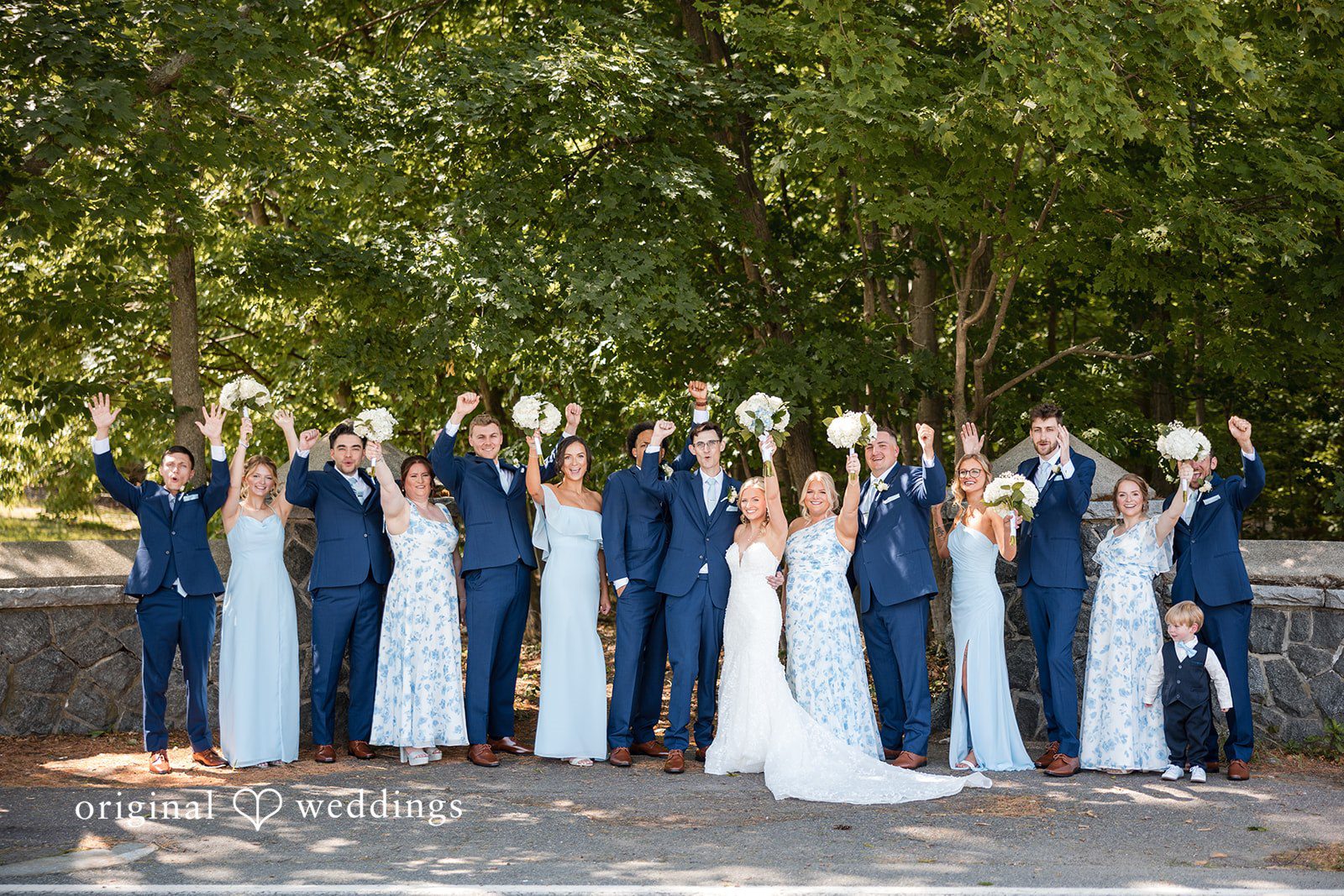 John + Emma Wedding party posing together with their arms raised high.
