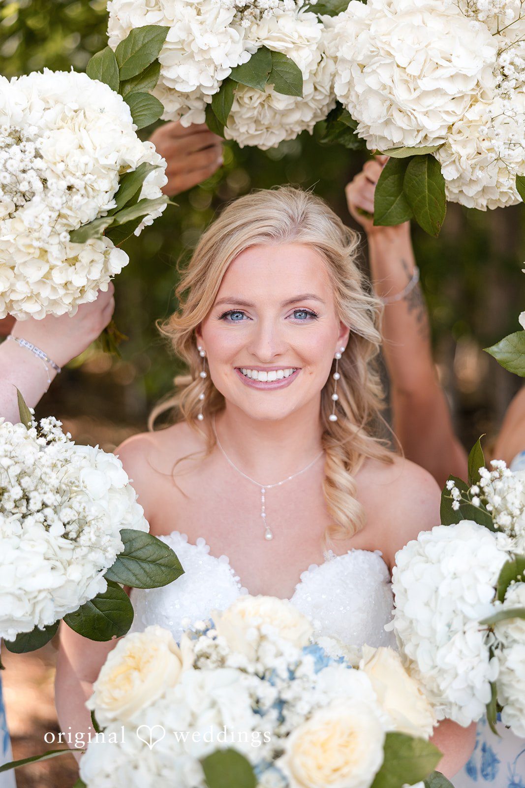 John + Emma Close-up portrait of a smiling bride framed by white flowers.