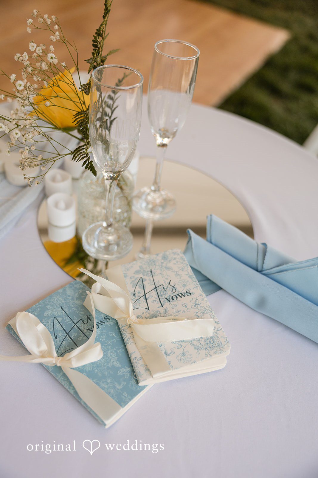 John + Emma Flat lay of wedding stationery, table settings, and light blue fabrics.