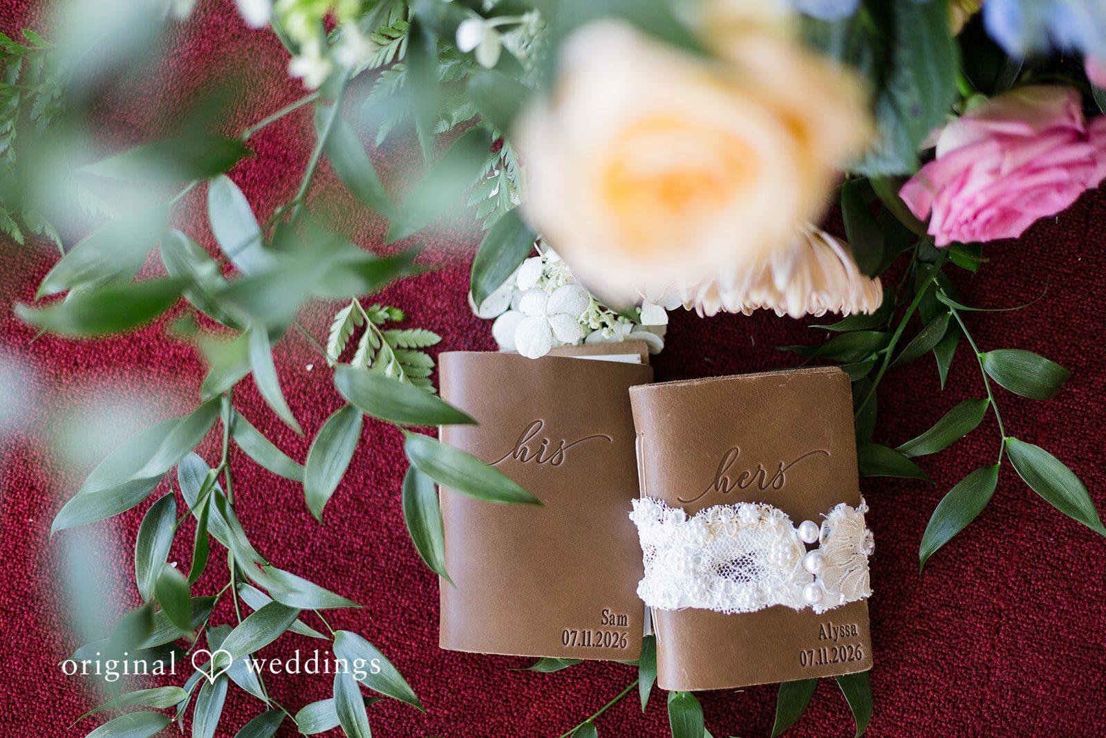 Close-up of personalized wedding vow books surrounded by fresh flowers at Memorial Union.