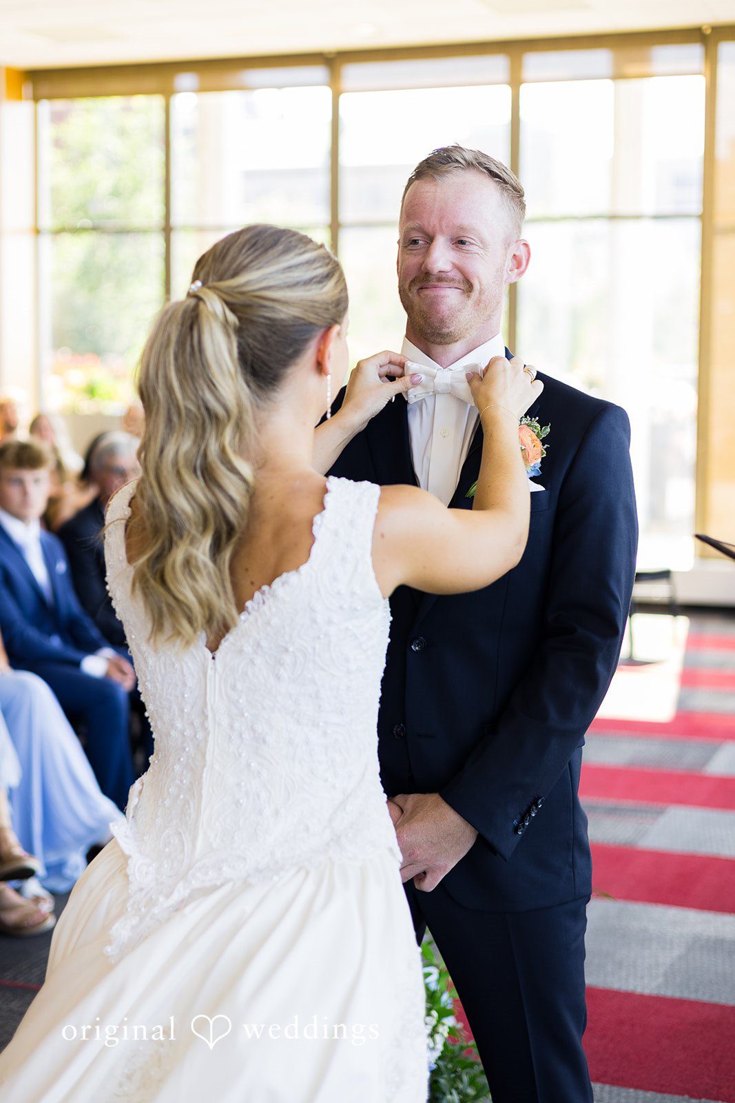Bride adjusting the groom's bow tie during the ceremony at Memorial Union