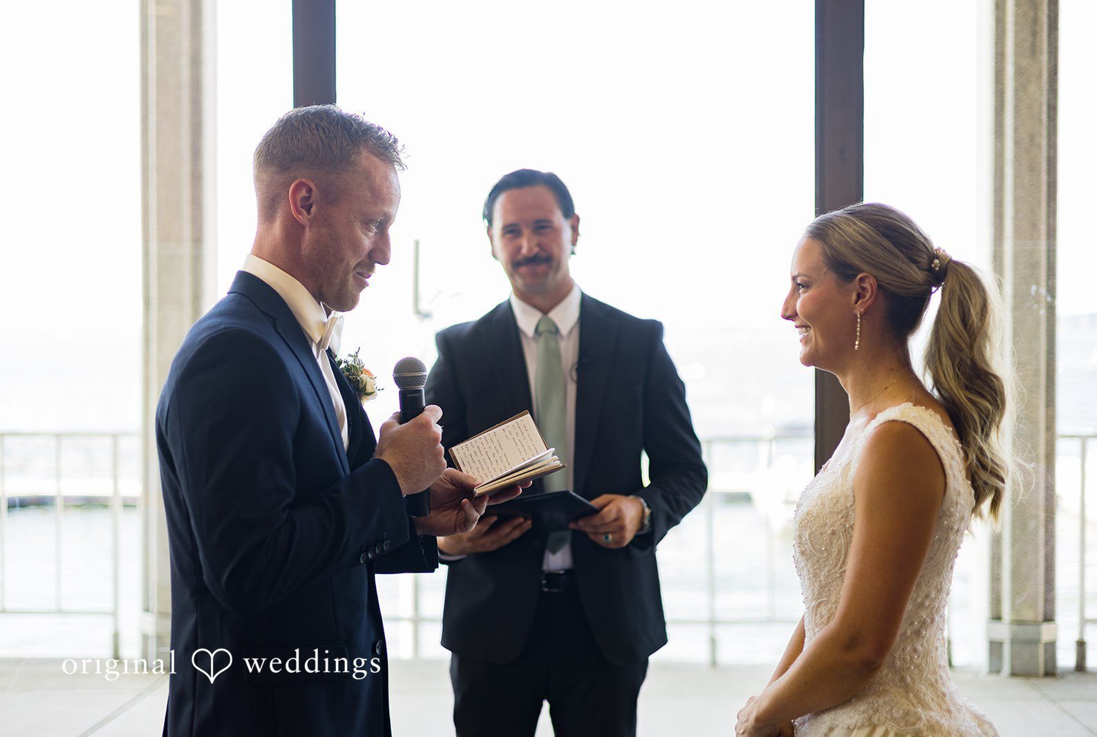 Couple looking at each other with smiles and groom reading a heartfelt note at Memorial Union captured by Madison Wedding Photographers from Original Weddings.