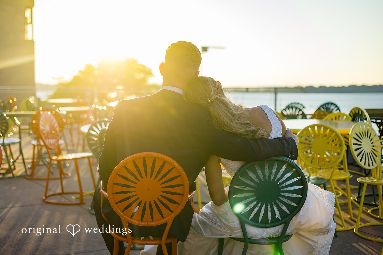 Newlyweds embracing while watching the sunset over the lake at Memorial Union.