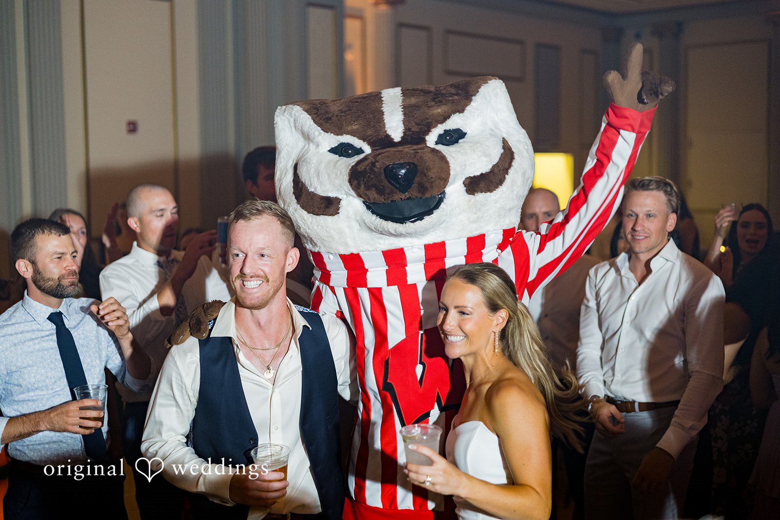 Bride and groom celebrating with Bucky Badger at Memorial Union captured by Madison Wedding Photographers from Original Weddings.