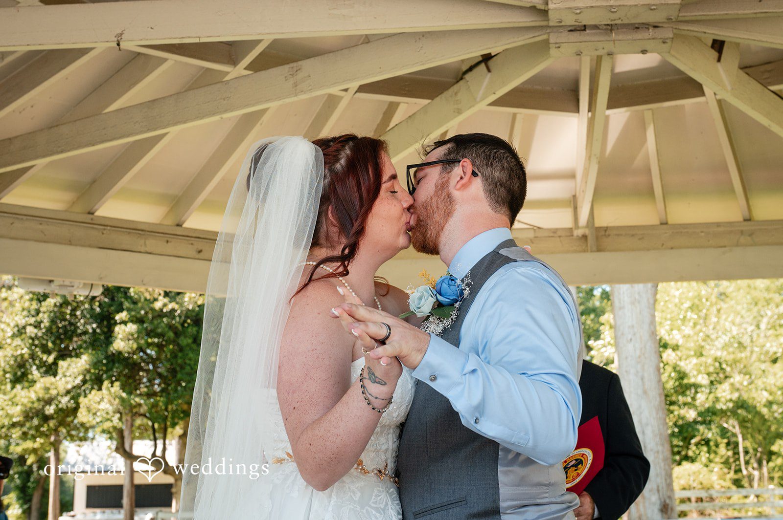 Joshua + Angela A bride and groom share their first kiss as husband and wife under a white gazebo.