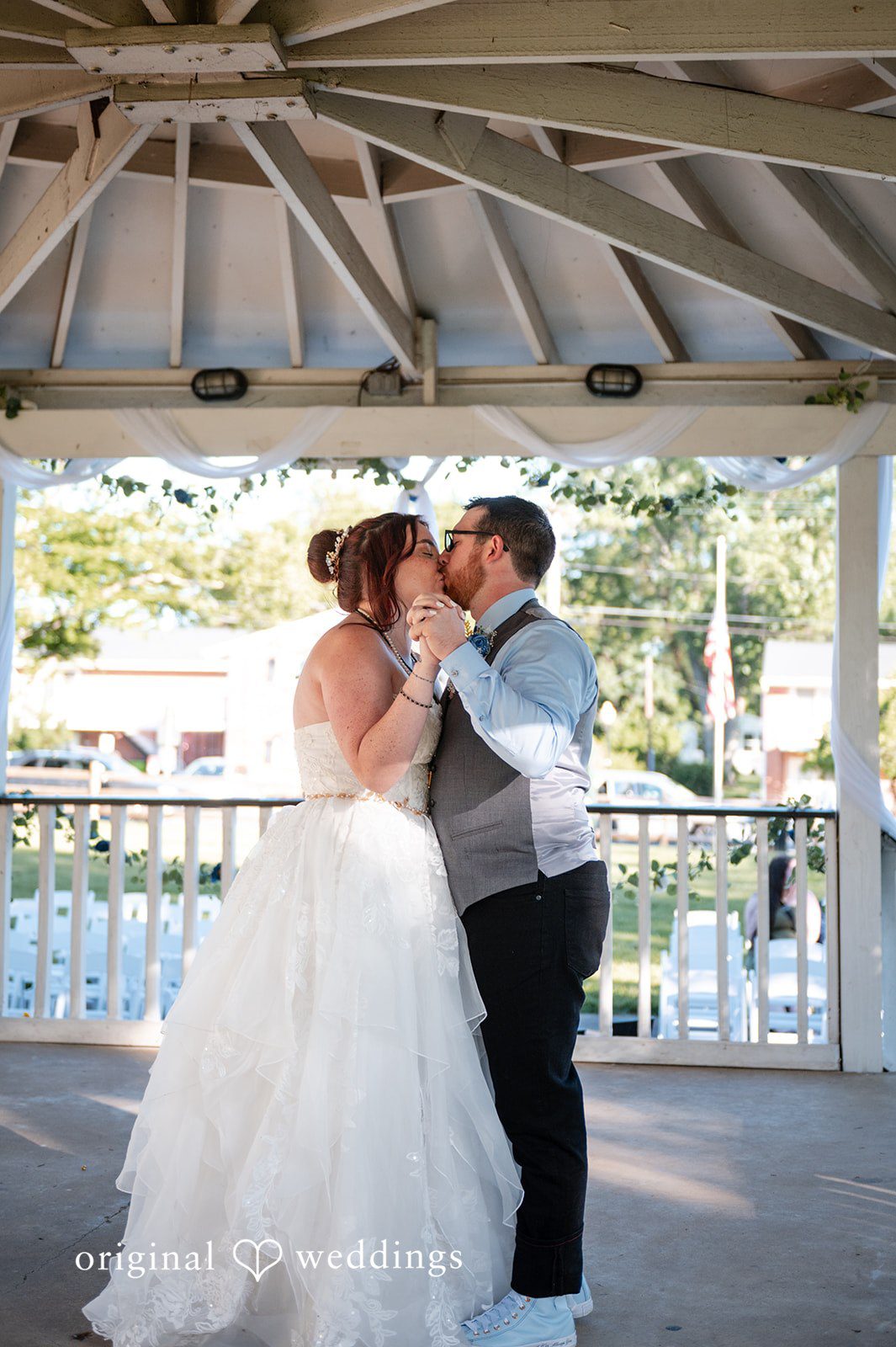 Joshua + Angela A bride and groom embracing and sharing a kiss inside a white gazebo.