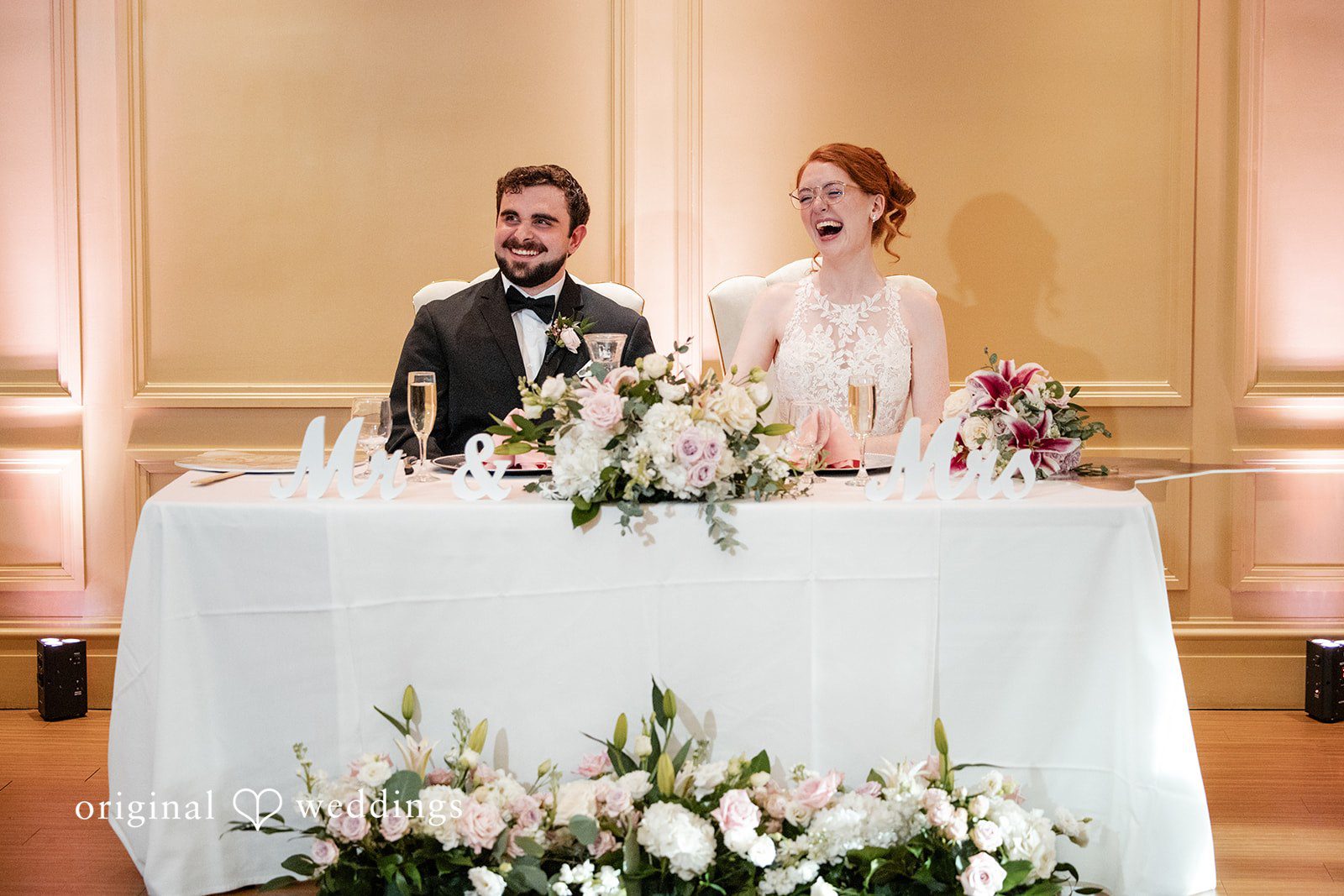 Aislyn + Alex Bride and groom sitting together at a flower-adorned sweetheart table.