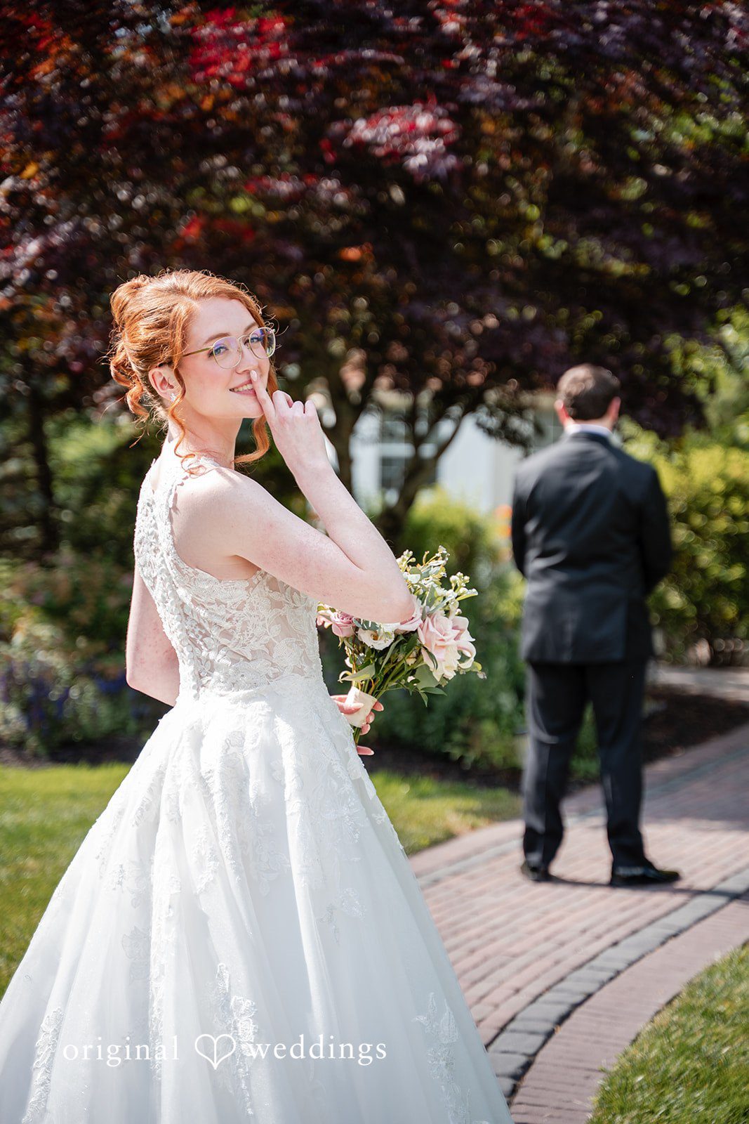 Aislyn + Alex Bride holding a finger to her lips while approaching the groom from behind for a first look reveal.