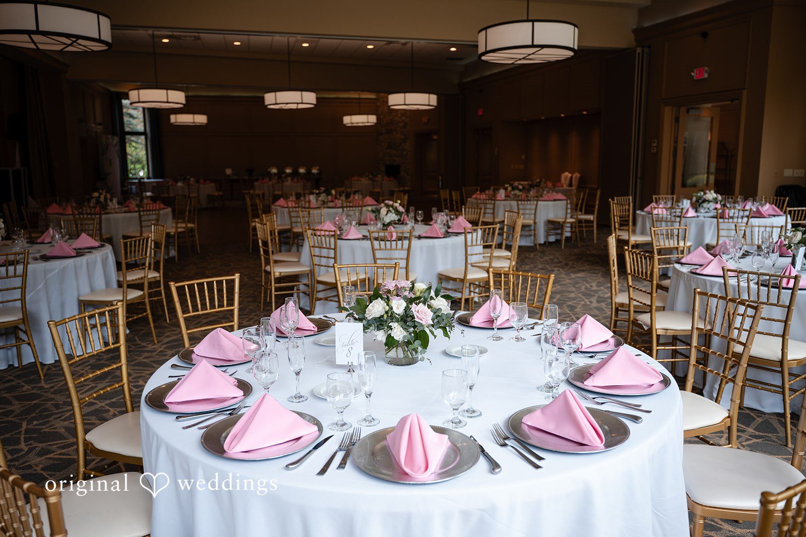 Aislyn + Alex Wedding reception table set with pink napkins, silverware, and a central flower arrangement.