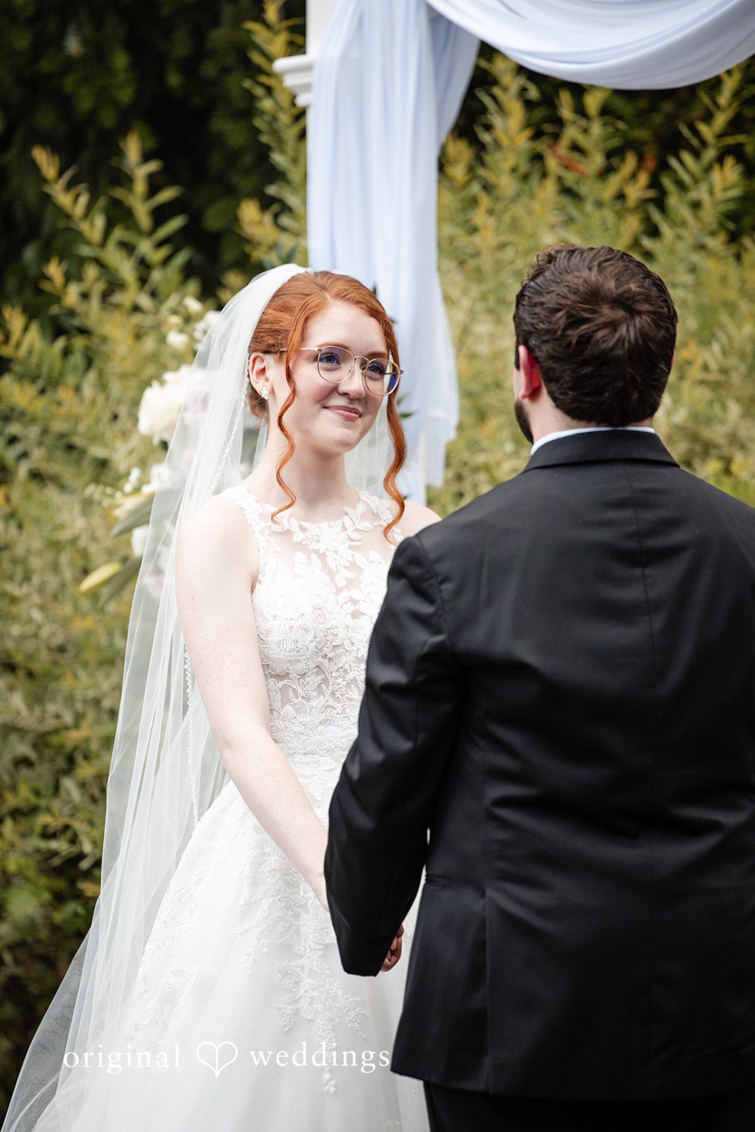 Aislyn + Alex Bride smiling at the groom during their wedding ceremony.