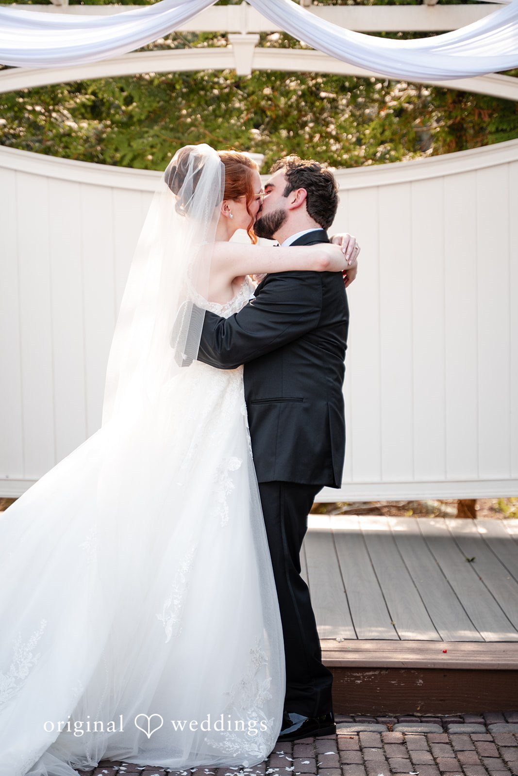 Aislyn + Alex Bride and groom embracing and sharing a kiss at the altar.