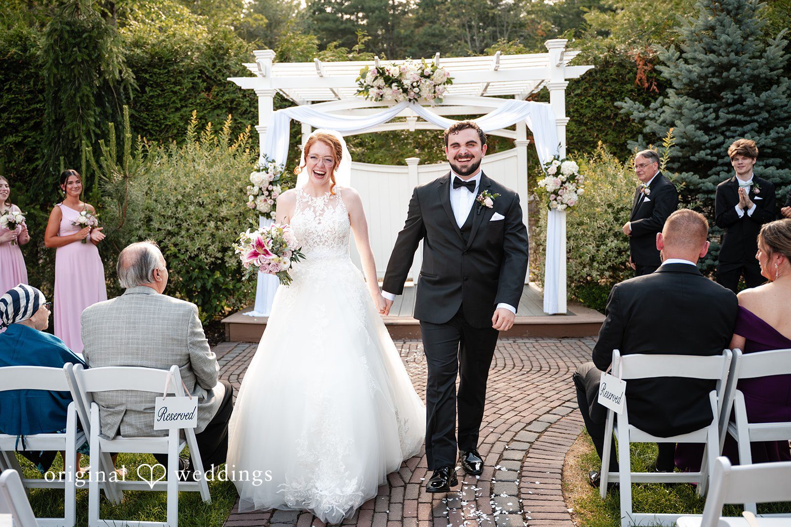 Aislyn + Alex Newlyweds walking down the aisle together as guests watch from their seats.
