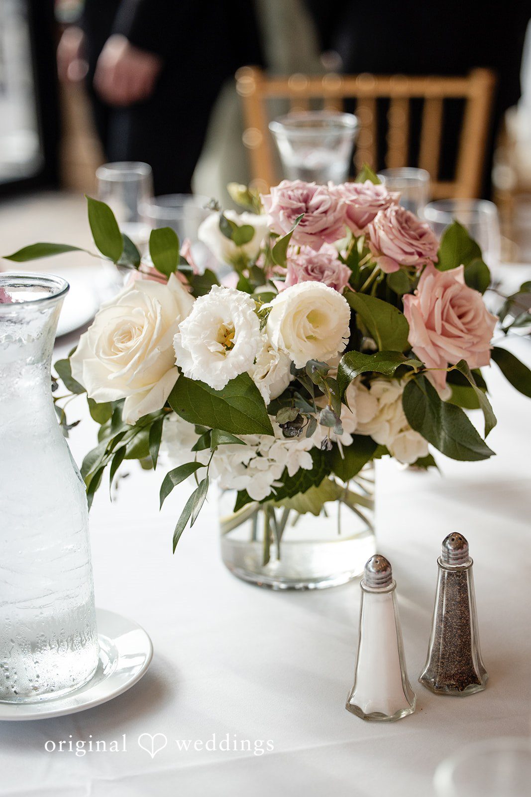 Aislyn + Alex Close-up of a floral centerpiece with white and pink flowers on a dining table.