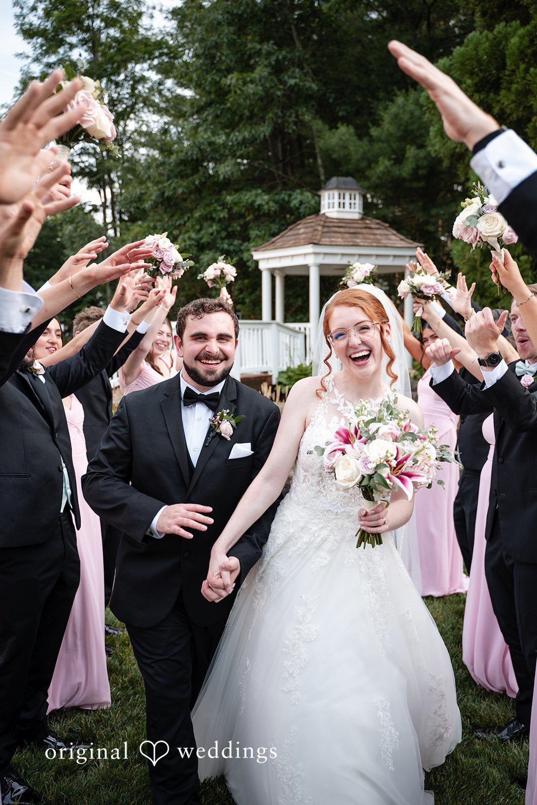 Aislyn + Alex Smiling newlyweds walking through a crowd of guests tossing flower petals.
