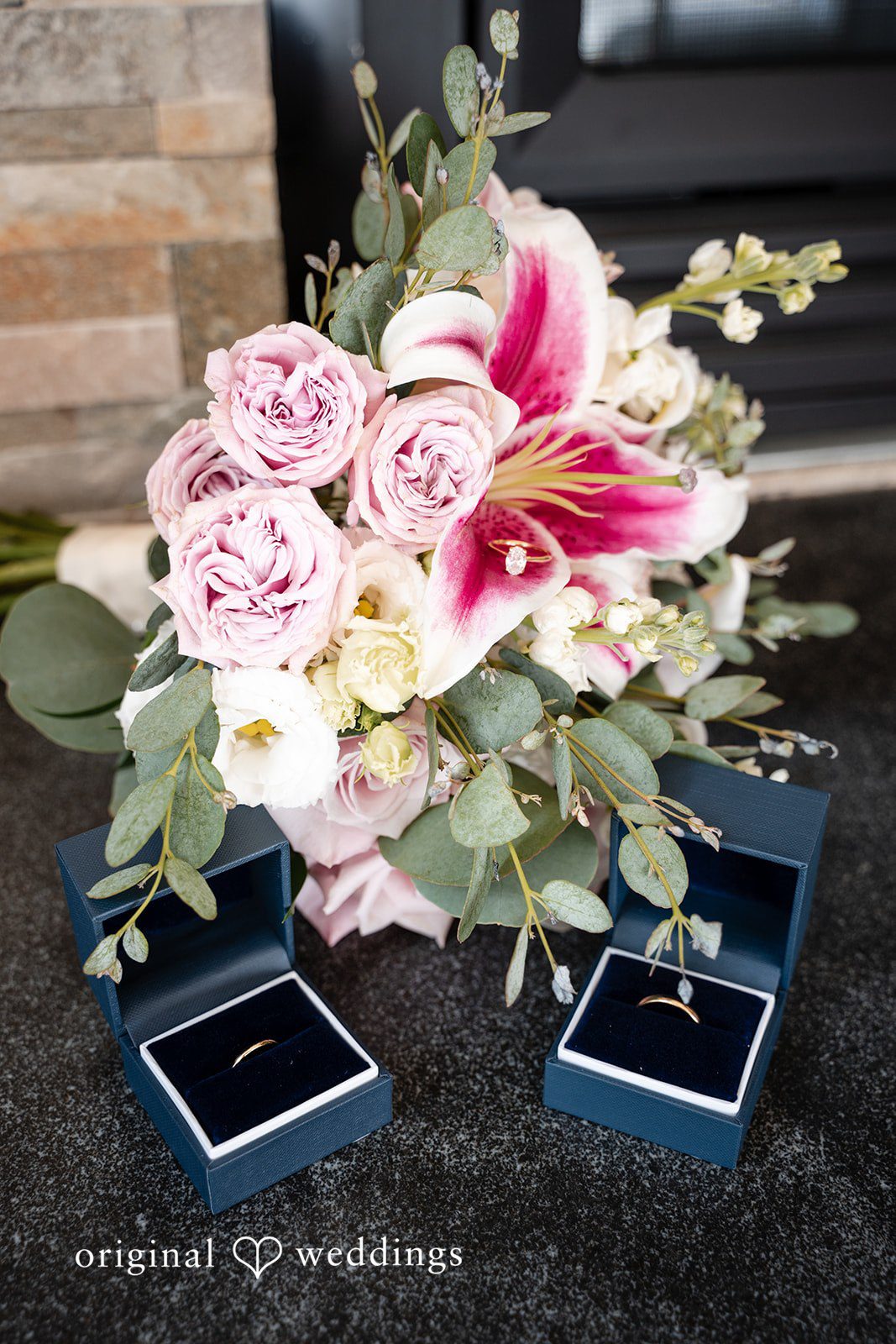 Aislyn + Alex Bridal bouquet with pink and white roses placed next to two black ring boxes.