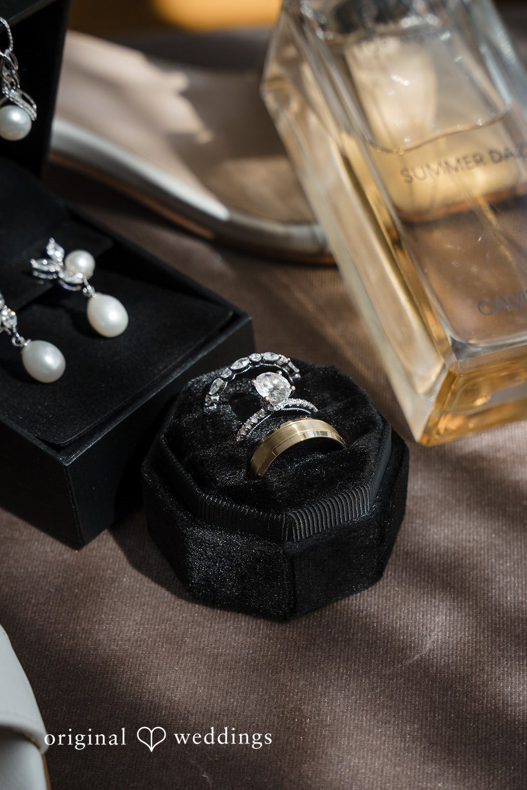 Ashley + Jonathan Close-up of wedding rings placed on top of a dark jewelry box.