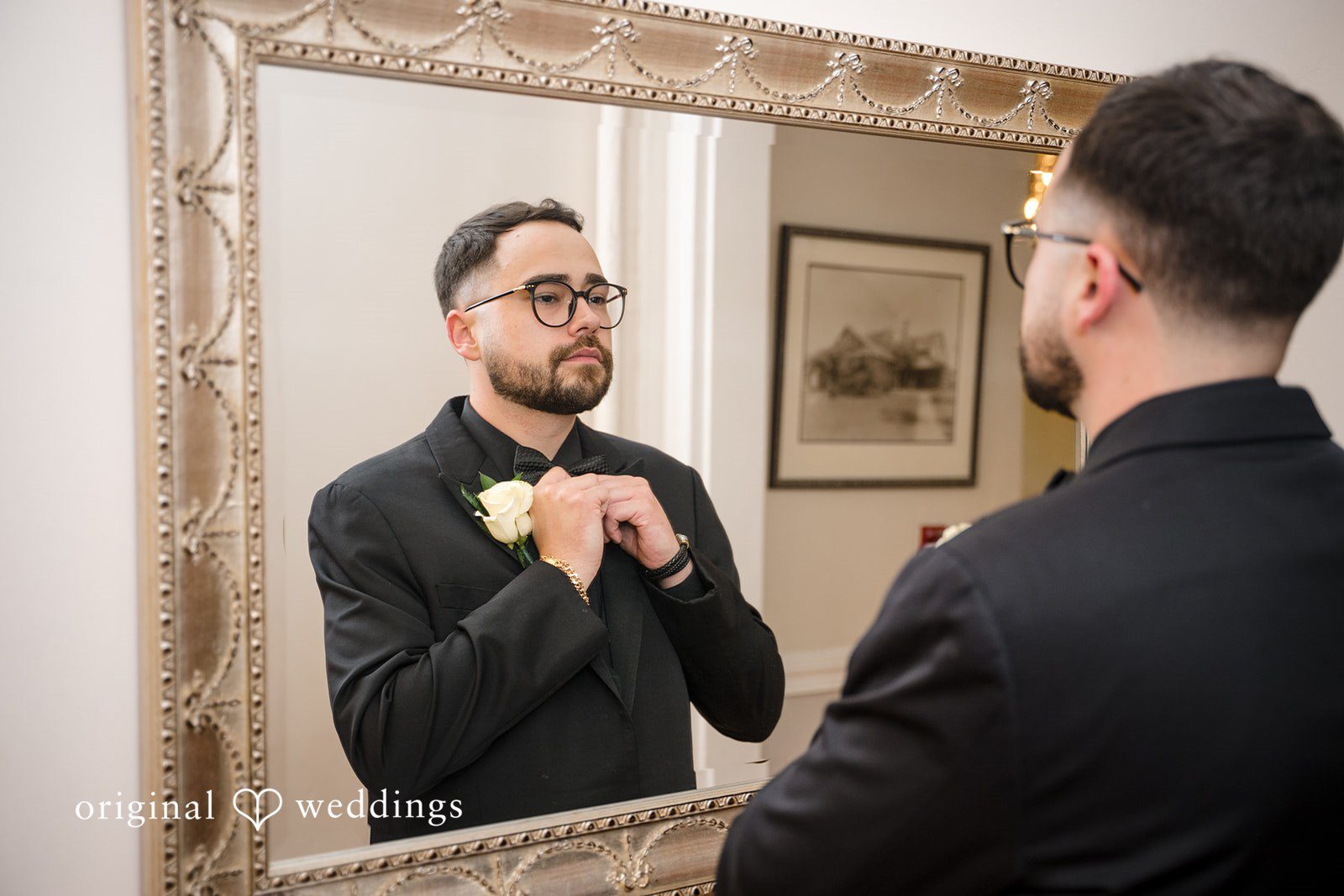 Ashley + Jonathan Groom adjusting his shirt collar while looking at himself in a mirror.