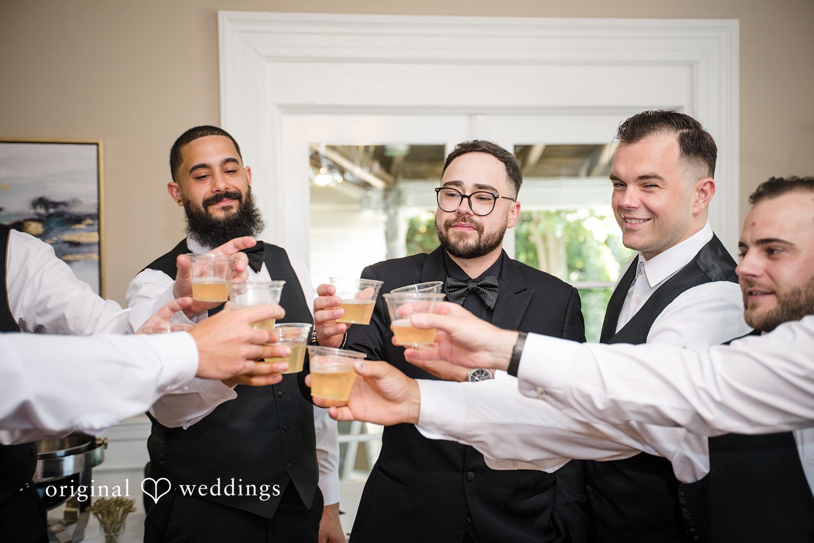 Ashley + Jonathan Group of groomsmen gathered together raising their glasses for a toast.