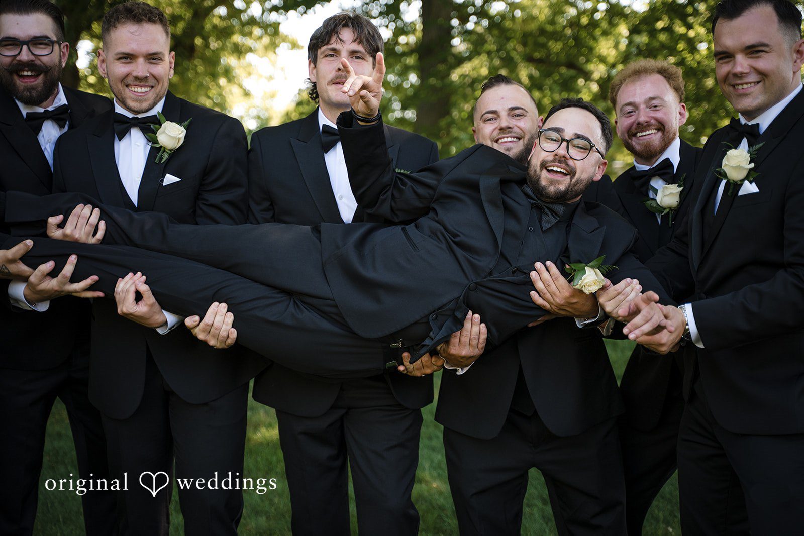 Ashley + Jonathan Groomsmen playfully lifting the groom up horizontally into the air.