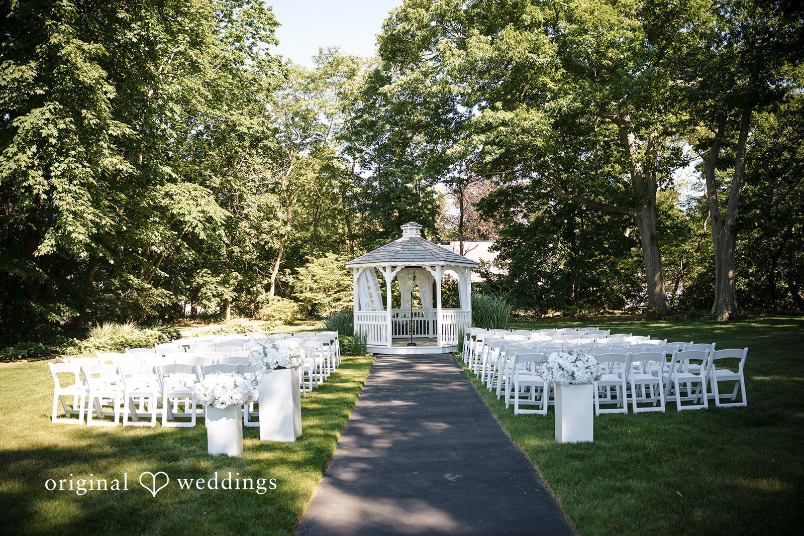 Ashley + Jonathan Empty wedding ceremony seating arranged on a lawn leading to a white gazebo.