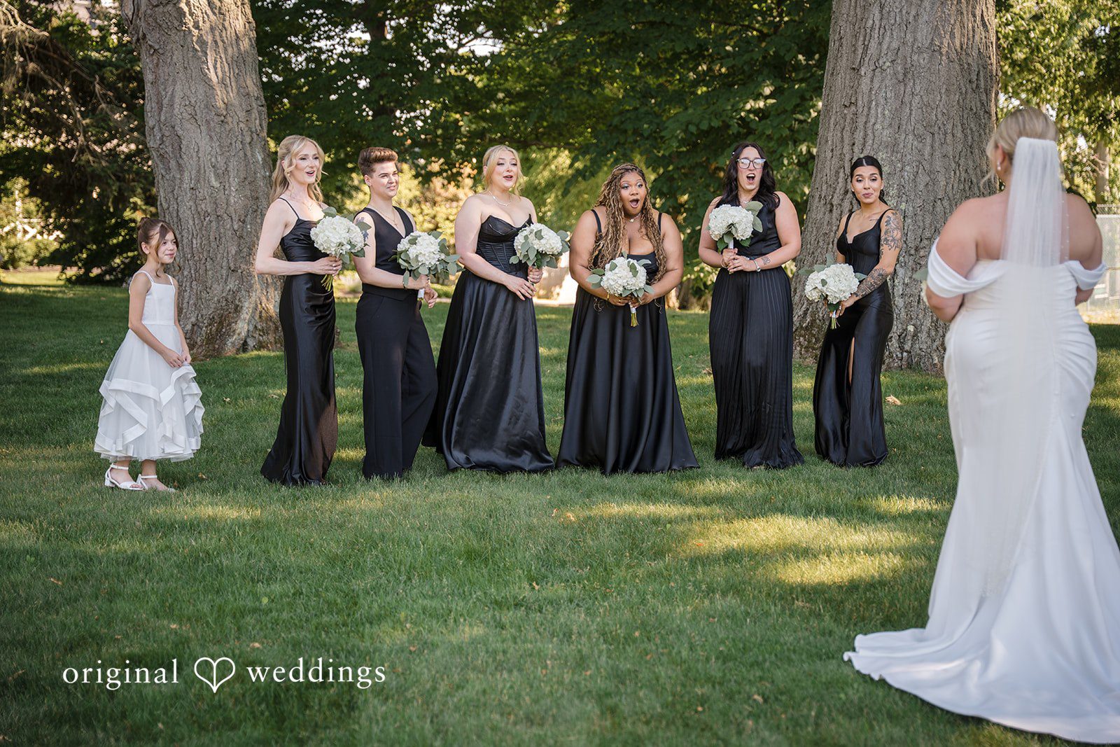 Ashley + Jonathan Bridesmaids standing in a line on a lawn next to the bride.