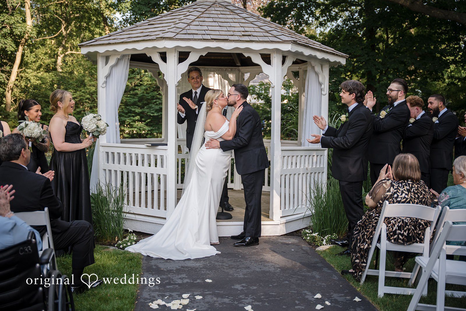 Ashley + Jonathan A bride and groom kissing under a white gazebo during a wedding ceremony.