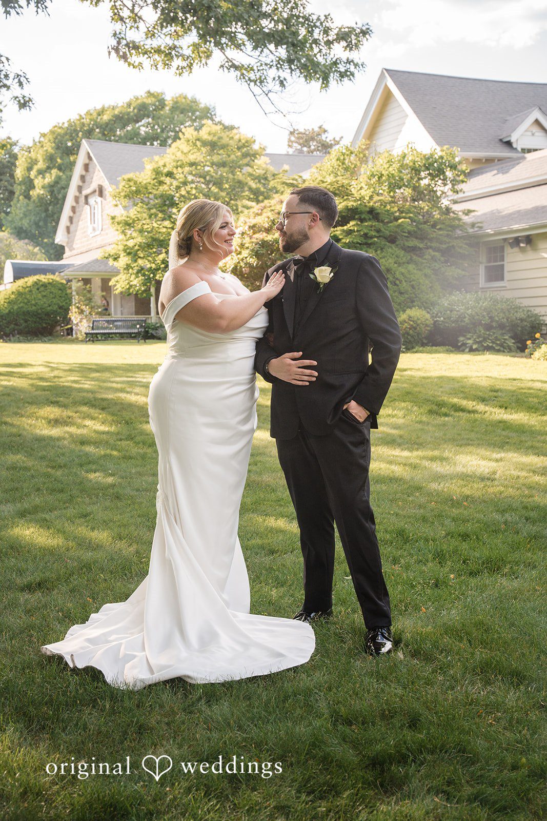Ashley + Jonathan A bride and groom holding hands and smiling at each other on a lawn.