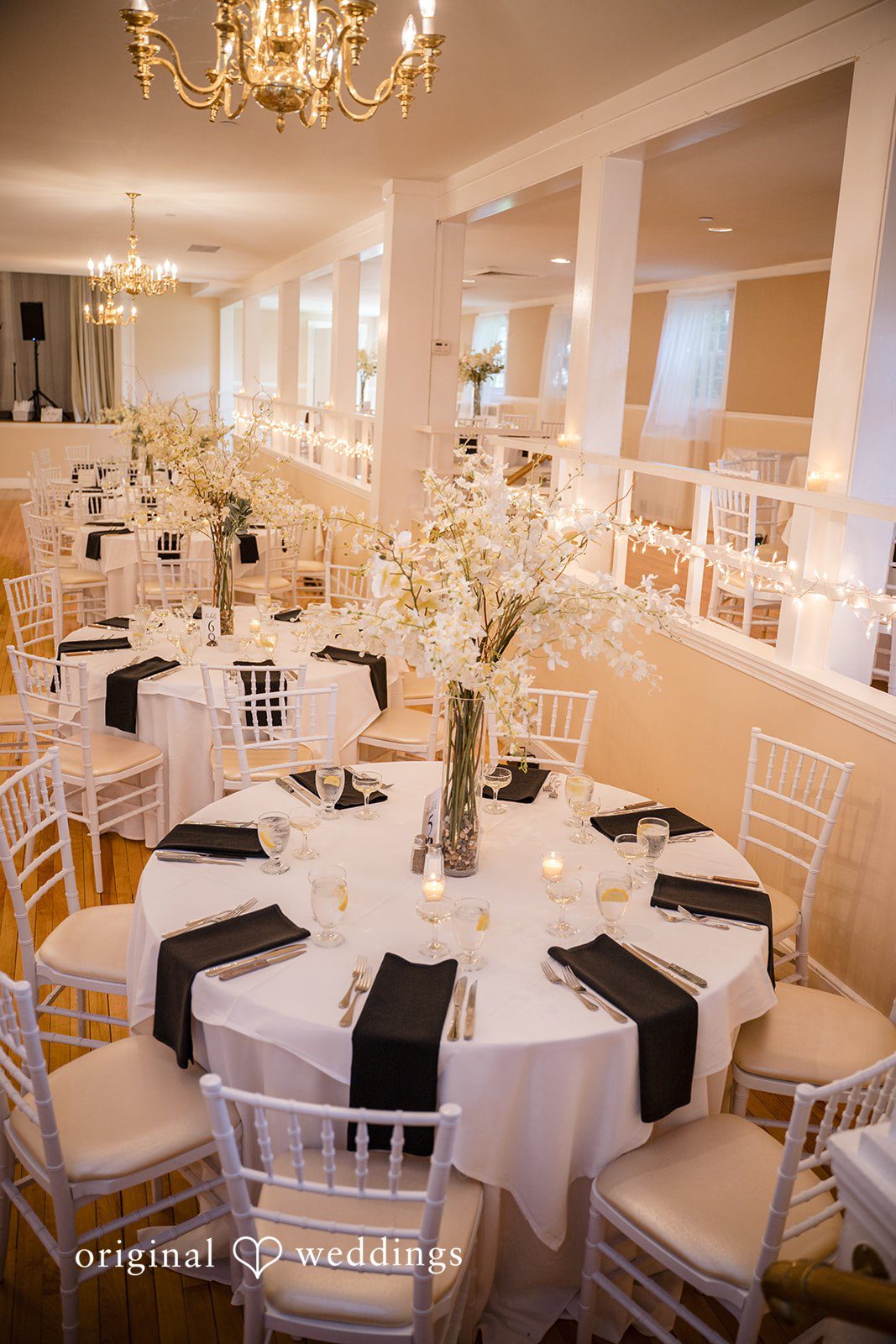 Ashley + Jonathan Banquet hall tables set with white tablecloths and black table runners.