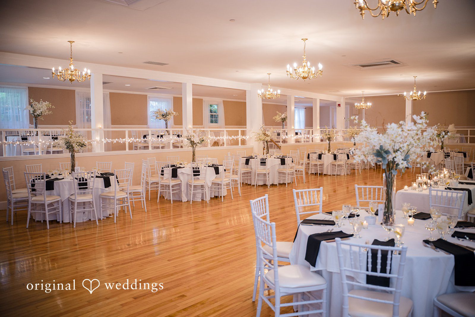 Ashley + Jonathan Well-lit wedding reception hall showing empty tables at Nahant Country Club.