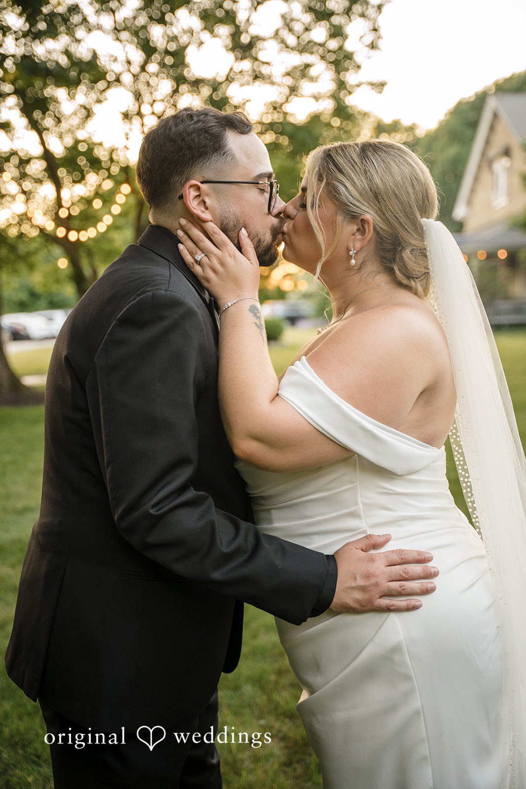 Ashley + Jonathan A bride and groom embracing and leaning in for a kiss outdoors.
