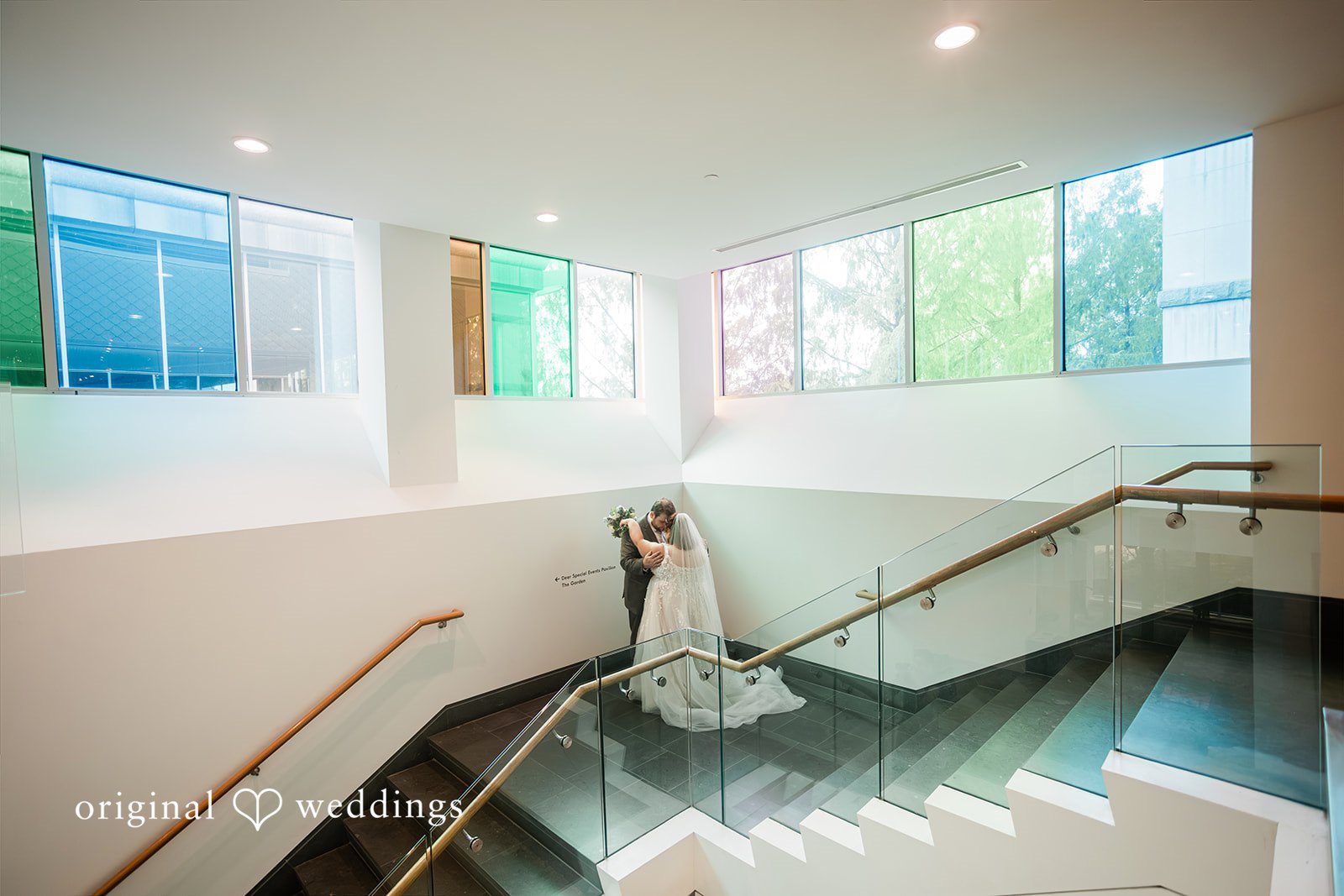 Grace + Nicholas A bride and groom embracing on a modern, bright staircase.