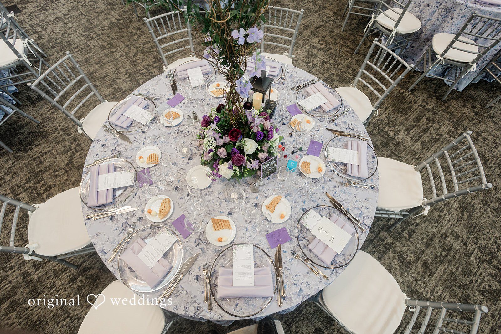 Grace + Nicholas An overhead view of a round reception table with a silver-gray tablecloth and a floral center arrangement.