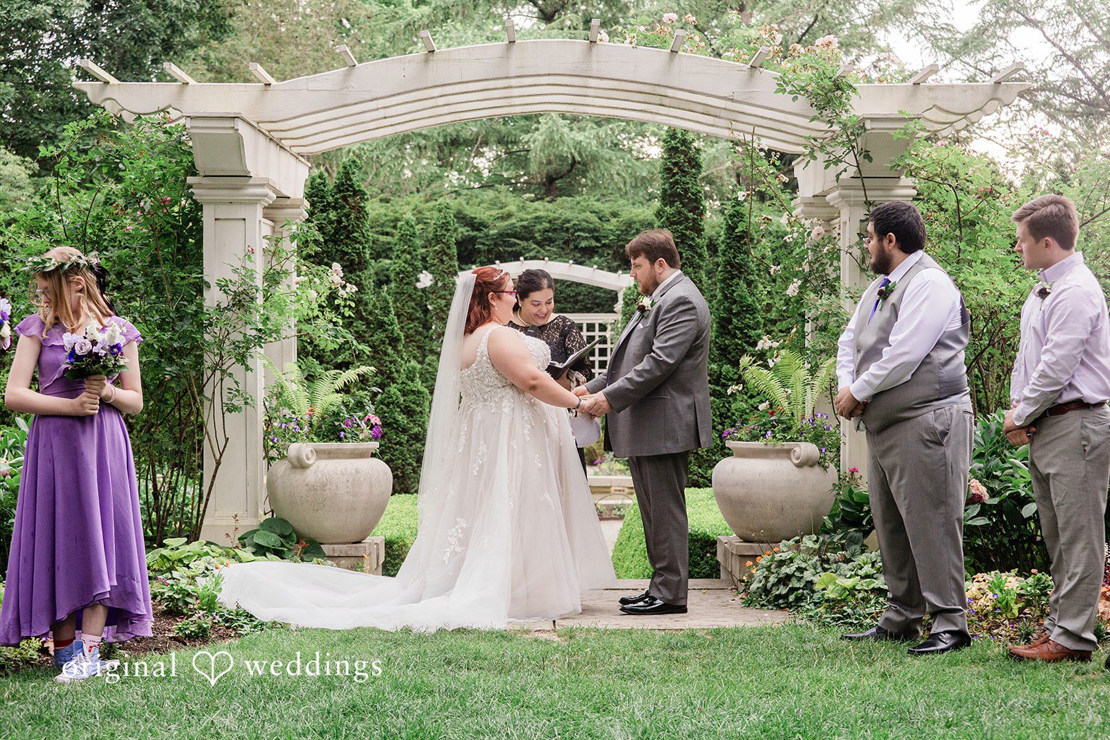 Grace + Nicholas A bride and groom exchanging vows under a stone archway during their wedding ceremony.