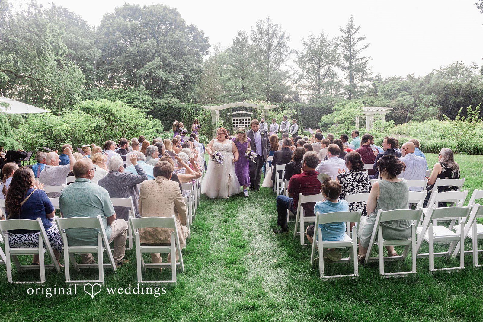 Grace + Nicholas Bride and groom walkin down an aisle and seated wedding guests watching a ceremony.
