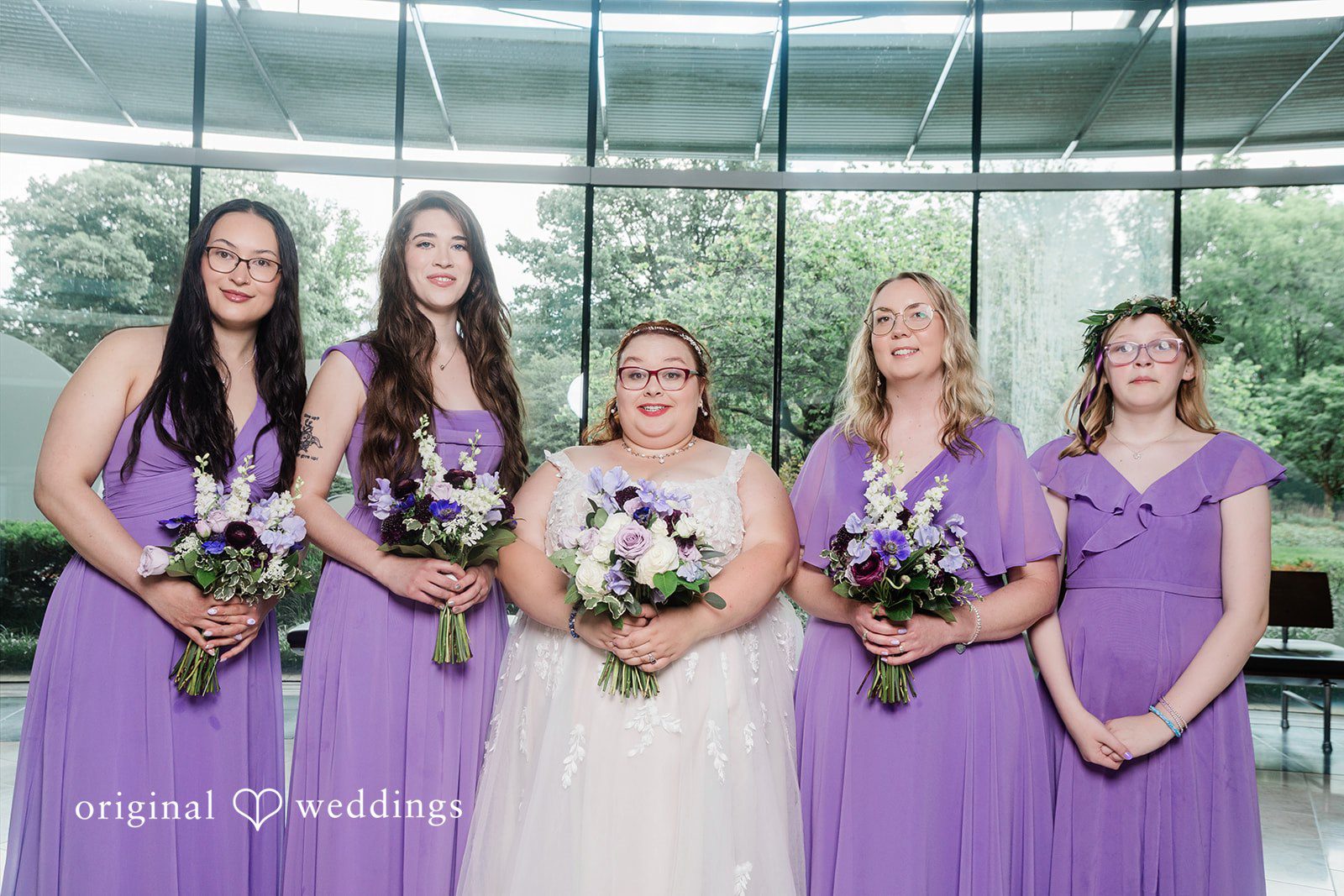 Grace + Nicholas A bride posing outdoors with four bridesmaids dressed in matching lavender gowns.