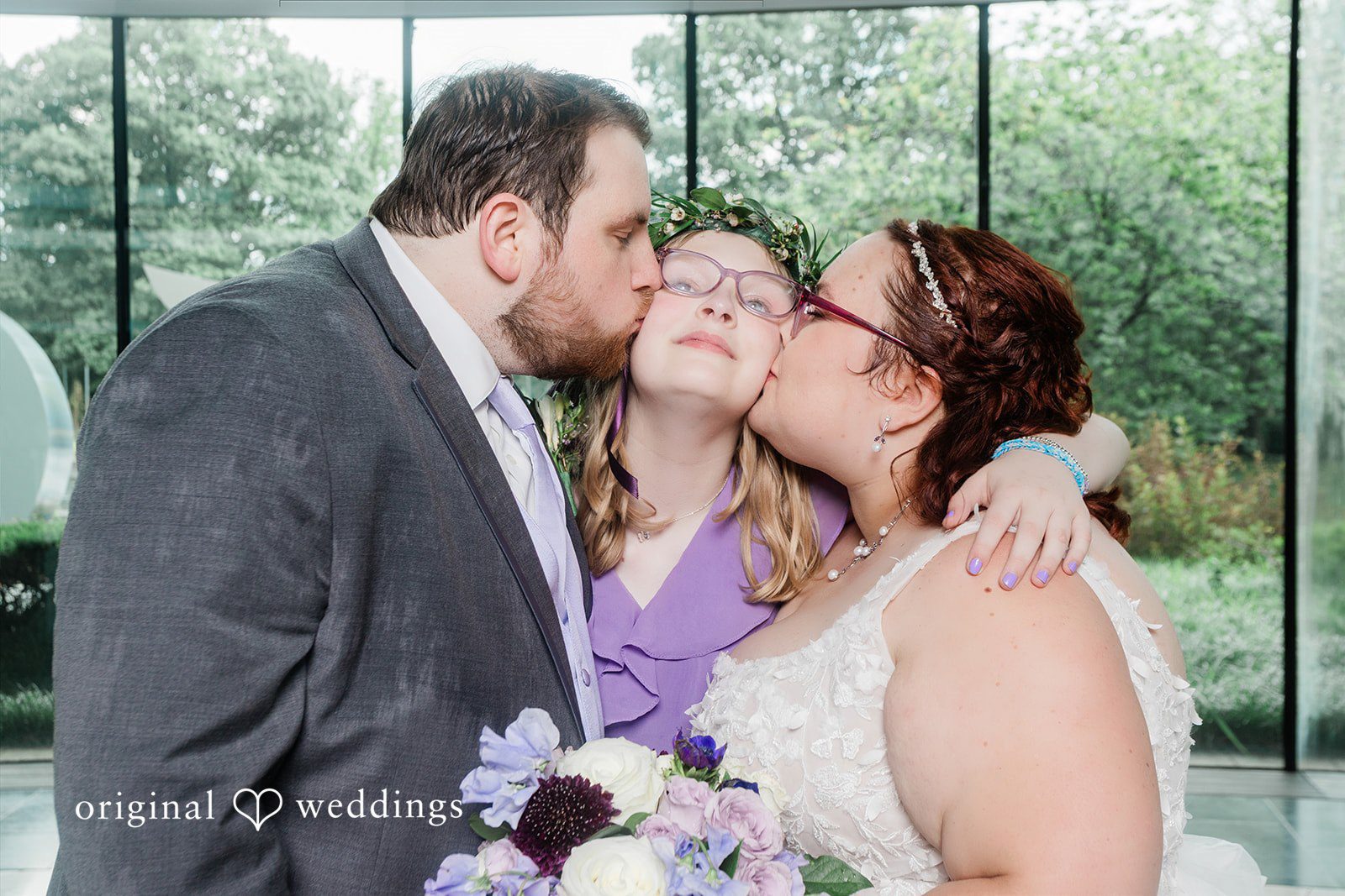 Grace + Nicholas A close-up of a groom and a woman kissing a smiling bride simultaneously on both cheeks.