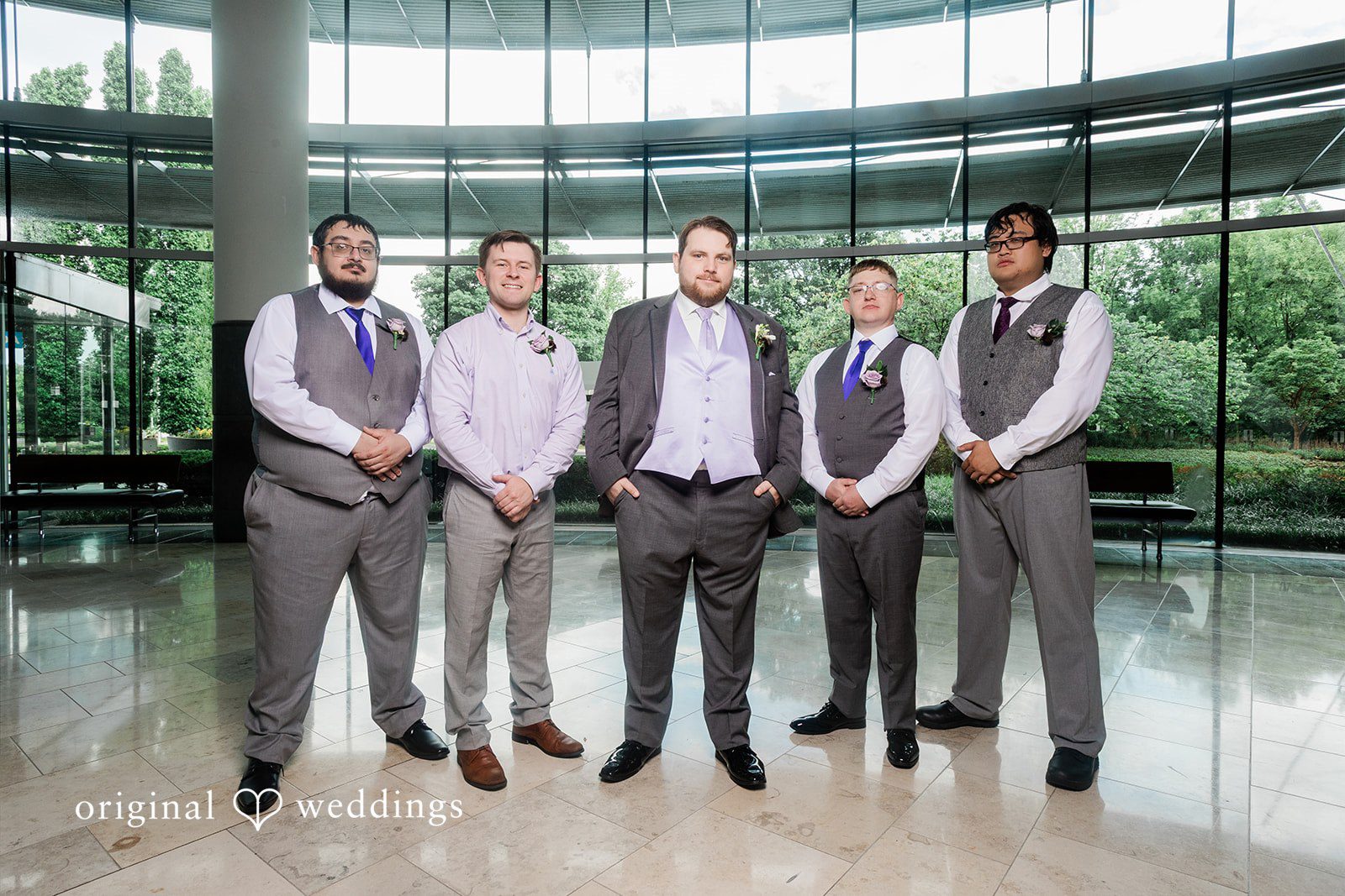 Grace + Nicholas A groom and his four groomsmen posing together in formal gray suits indoors.