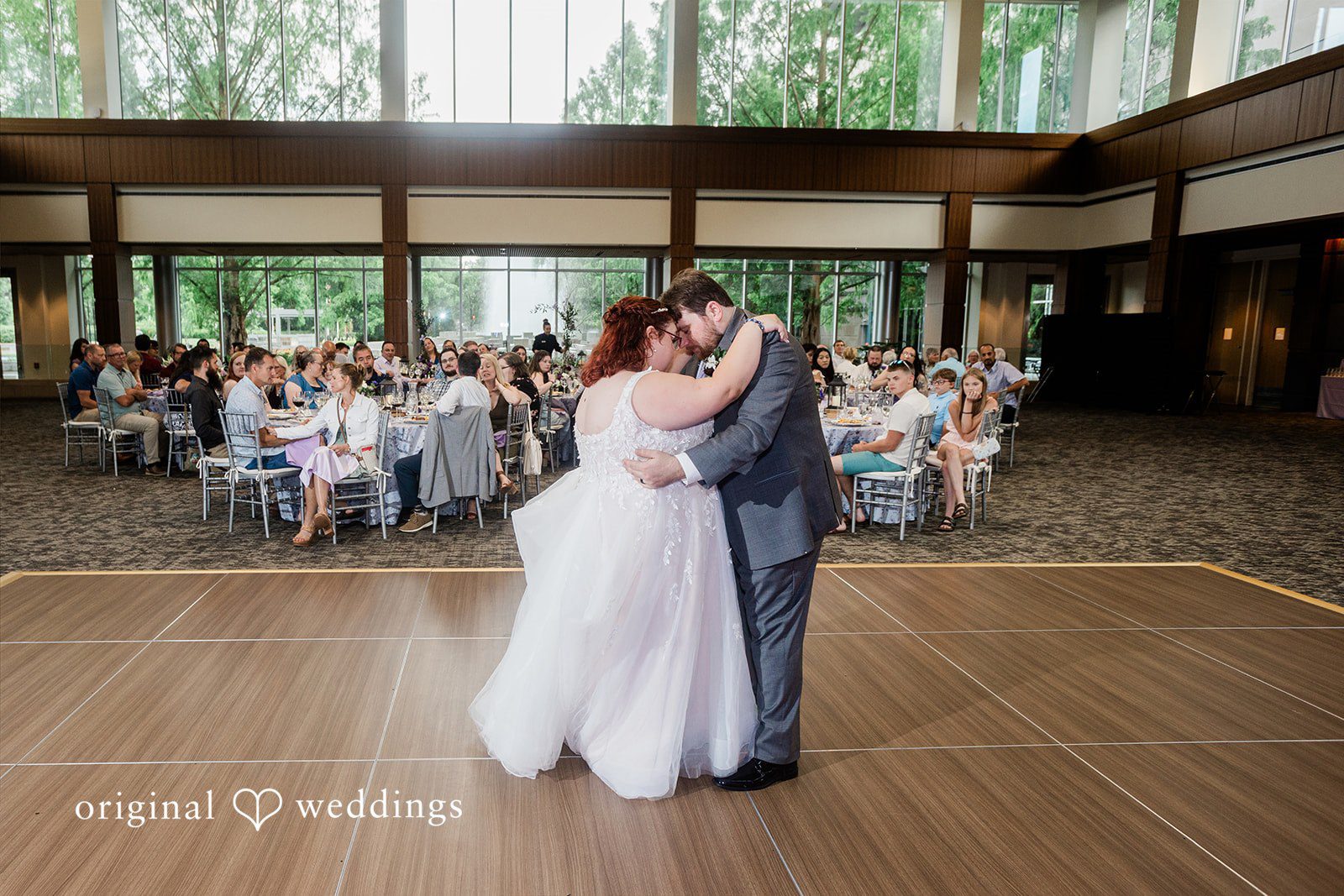 Grace + Nicholas A wide shot of a bride and groom embracing on a dance floor during their reception.
