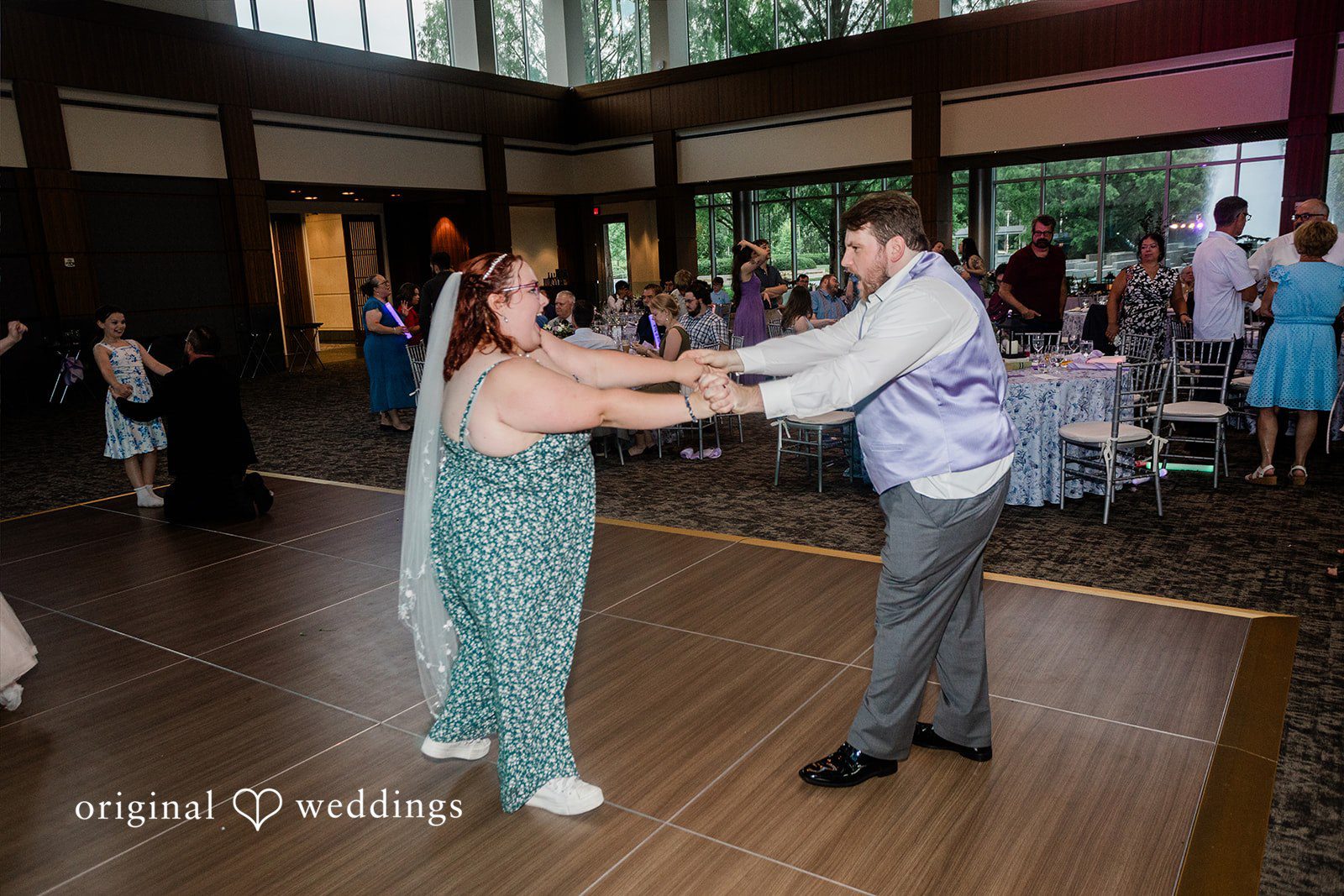 Grace + Nicholas A bride and groom dancing joyfully together on a wooden dance floor at their reception.