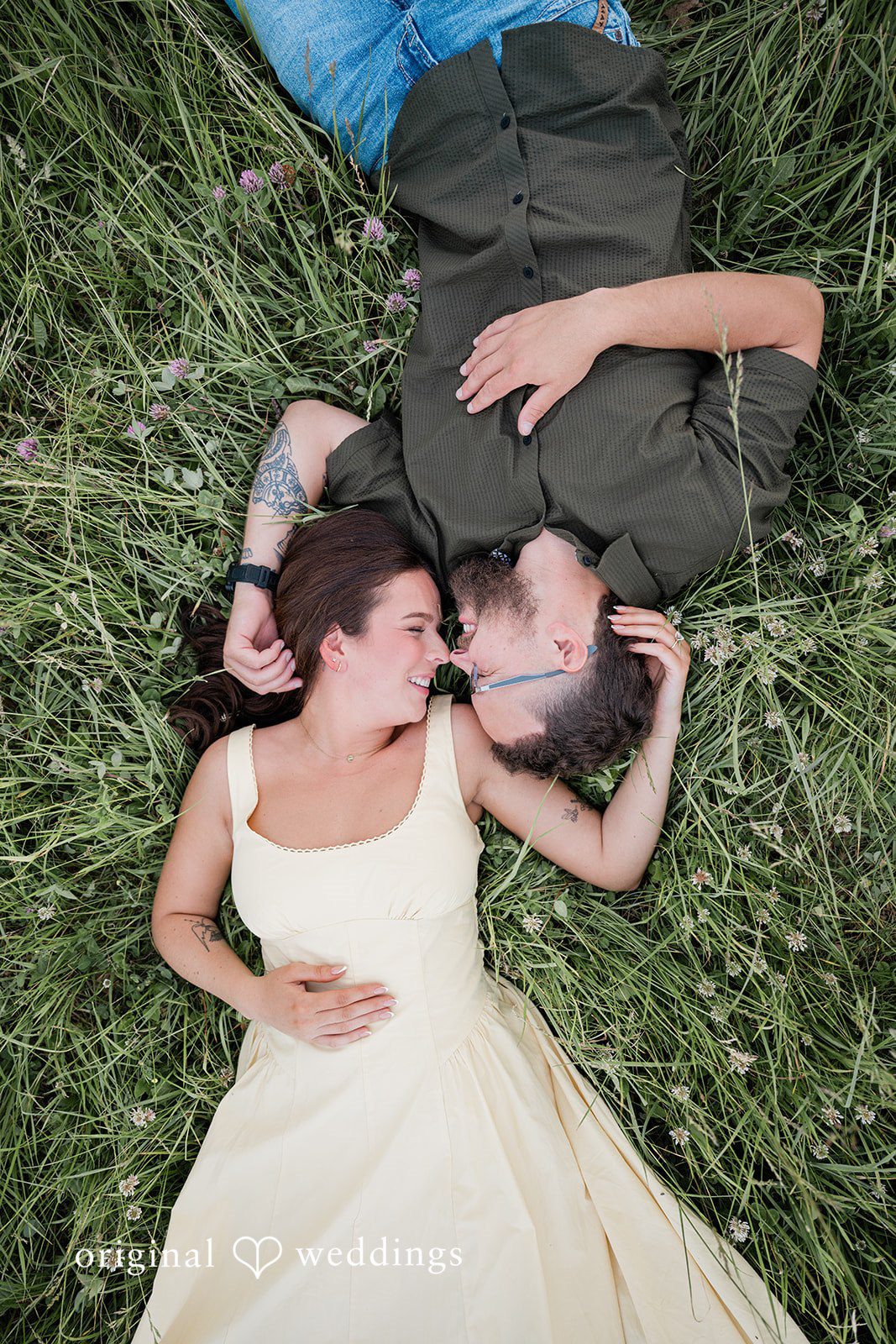 Andrea + Jordan An overhead bird's-eye view of a couple lying down together in a grassy field.