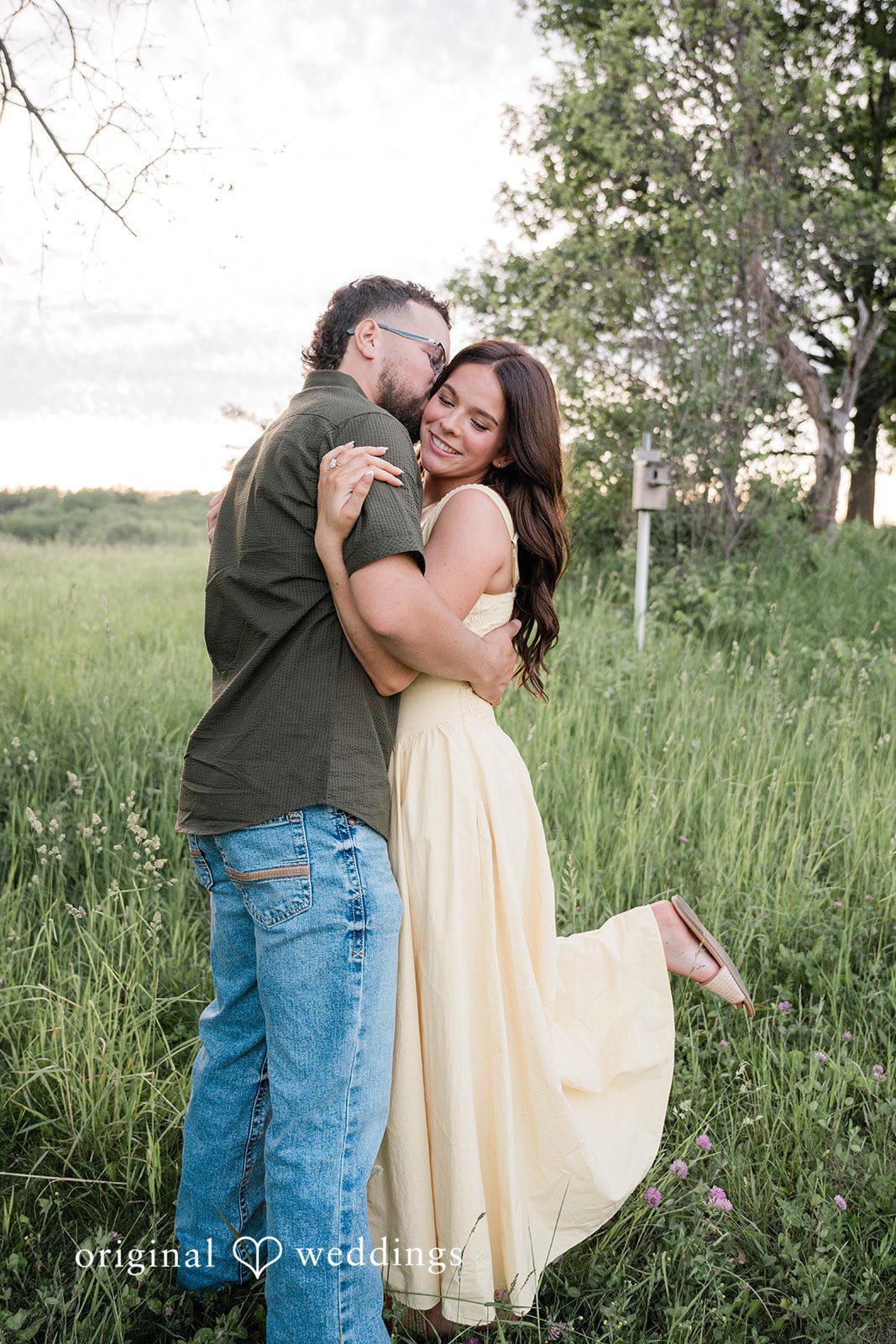 Andrea + Jordan A couple sharing a warm, tight embrace while standing in a grassy field.