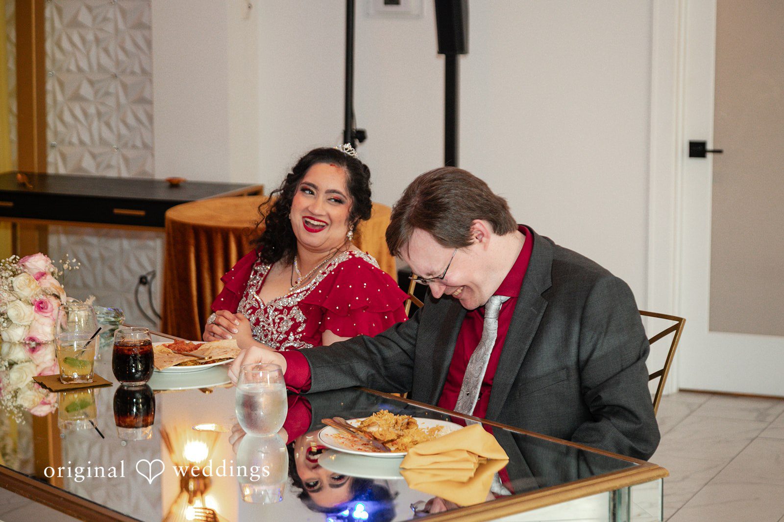 Anthony + Simi A bride and groom sitting together at reception table.