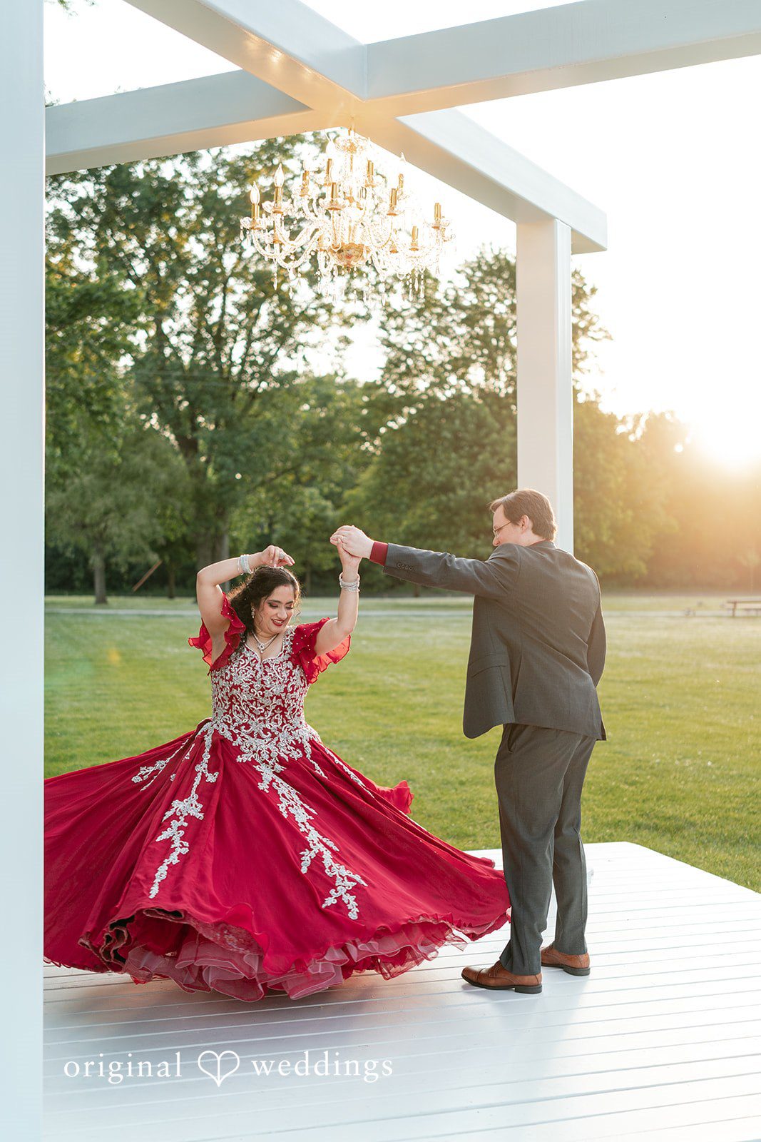 Anthony + Simi A bride spinning in a large red dress while a groom stands nearby.
