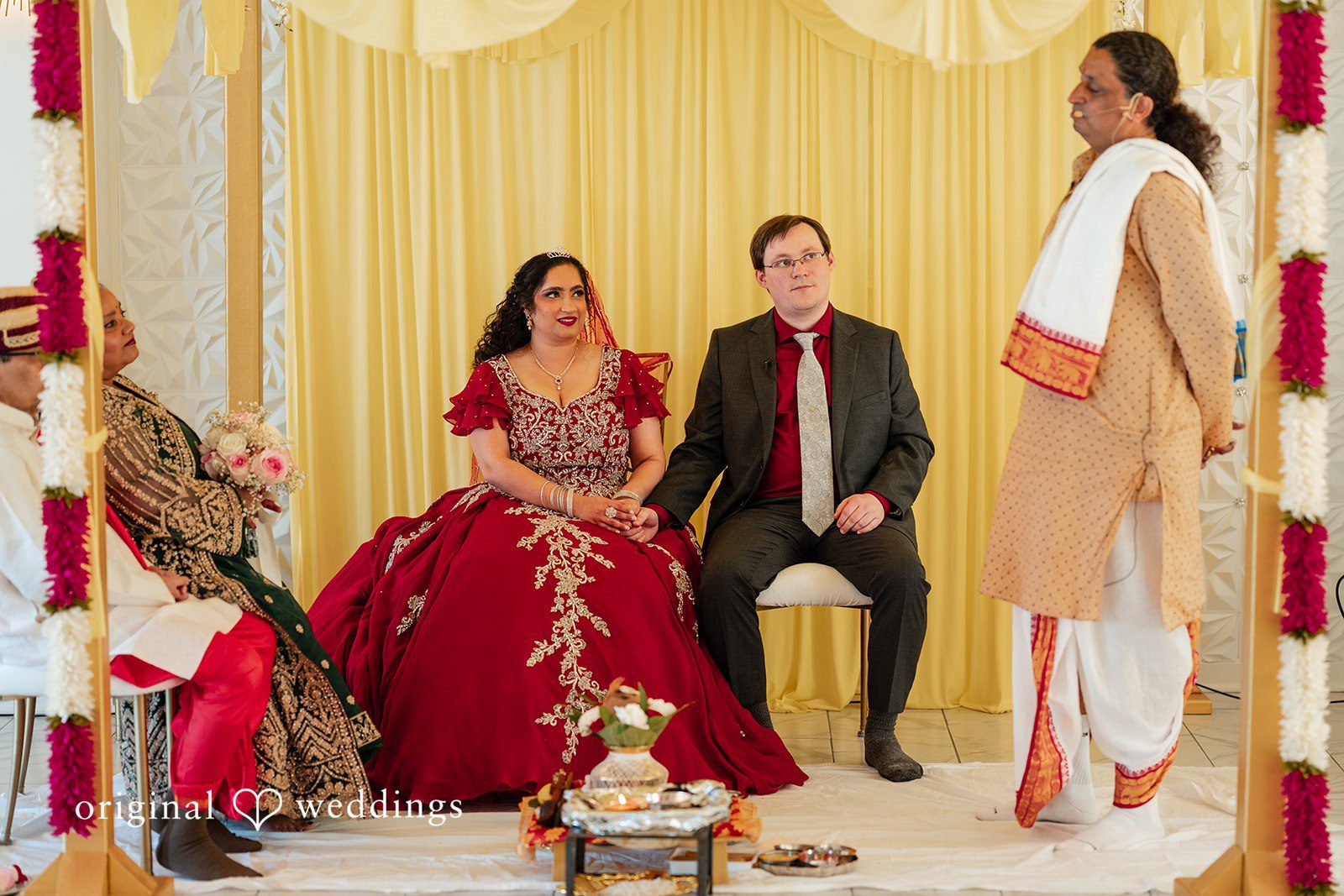 Anthony + Simi A bride and groom seated on a stage during a wedding ritual.