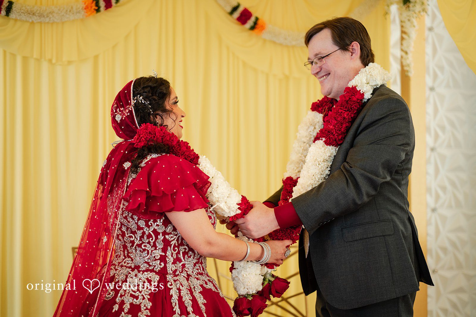 Anthony + Simi A bride and groom exchanging flower garlands during their wedding.